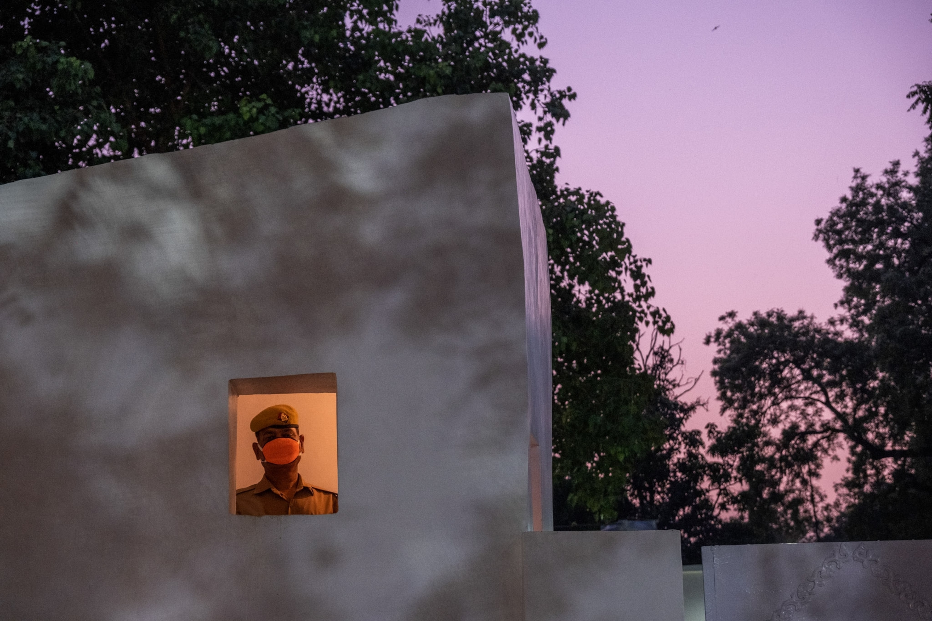 a man in the window of a cement building at sunset