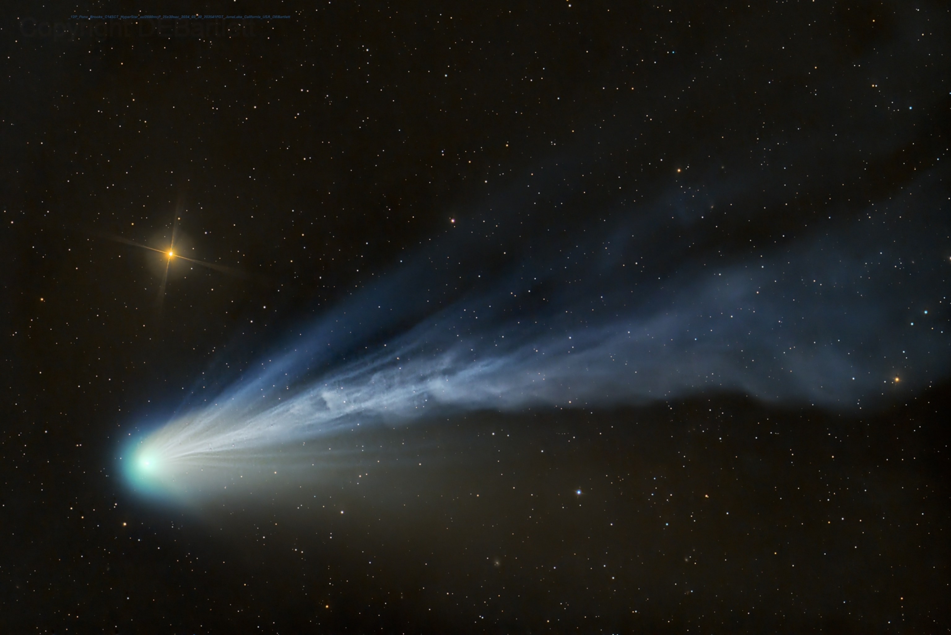 A bright blue comet and its cloud-like tail of particles, seen amongst the stars