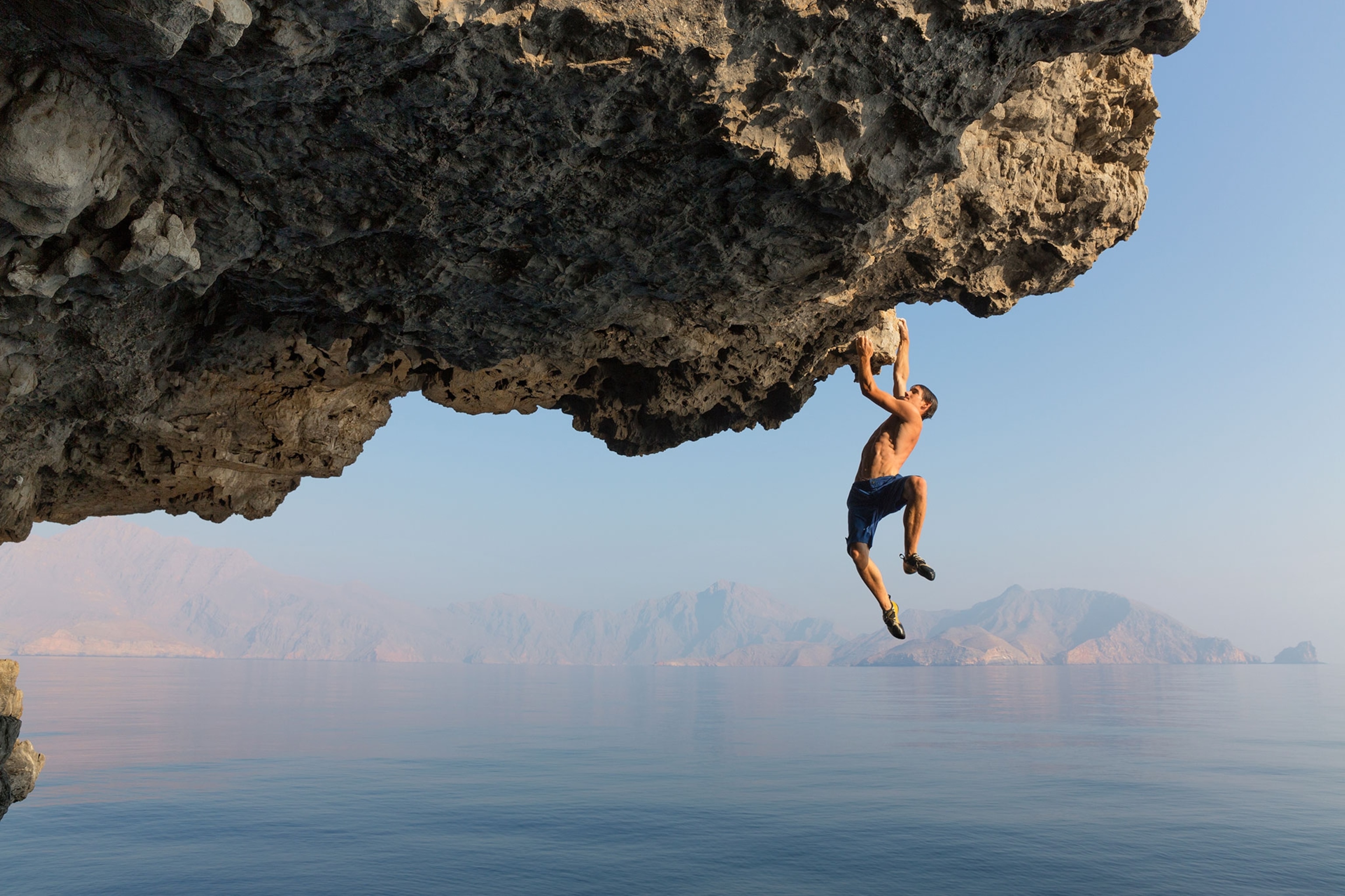 Alex Honnold hanging underneath a cliff