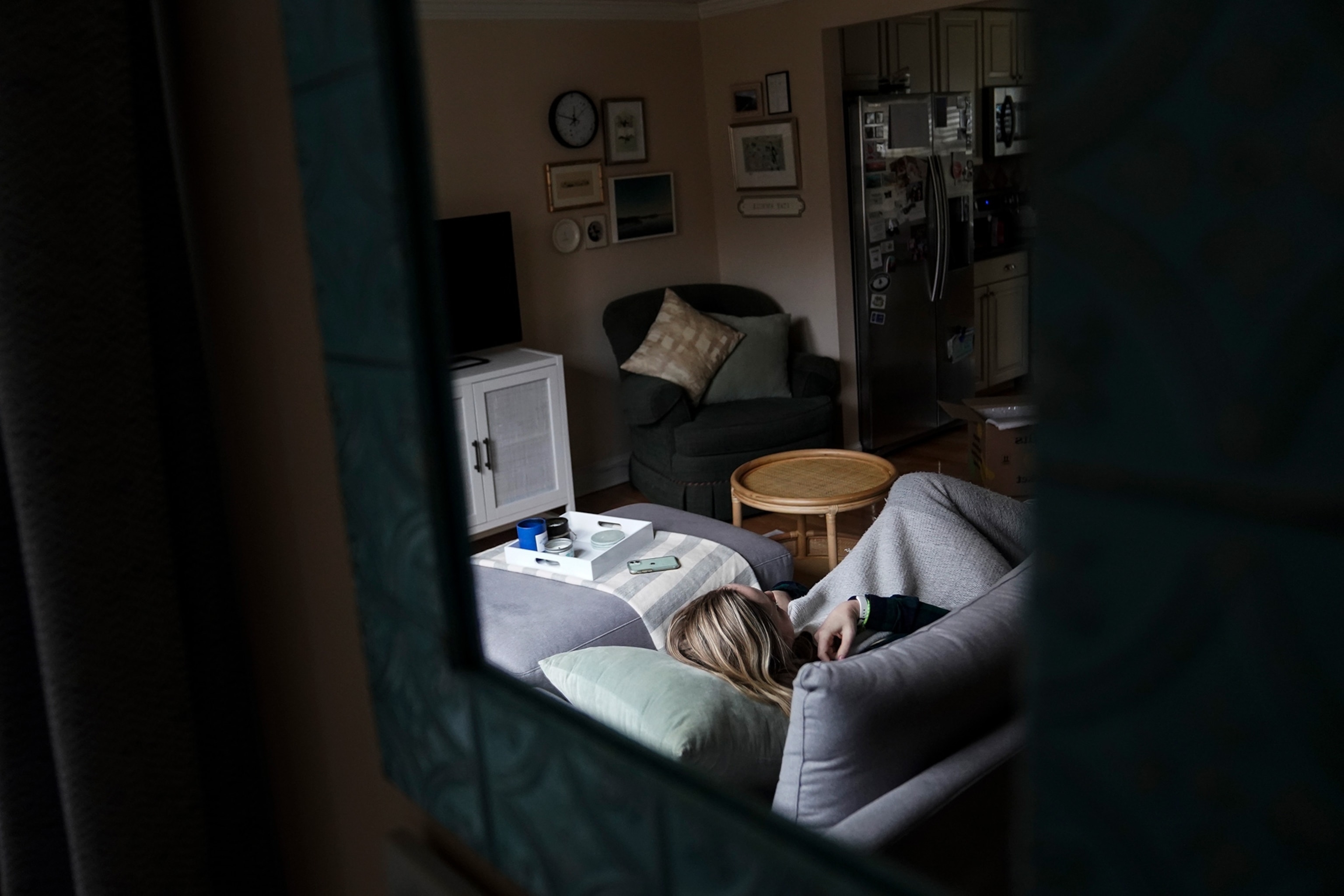 A woman with long covid rests on the coach in her home.