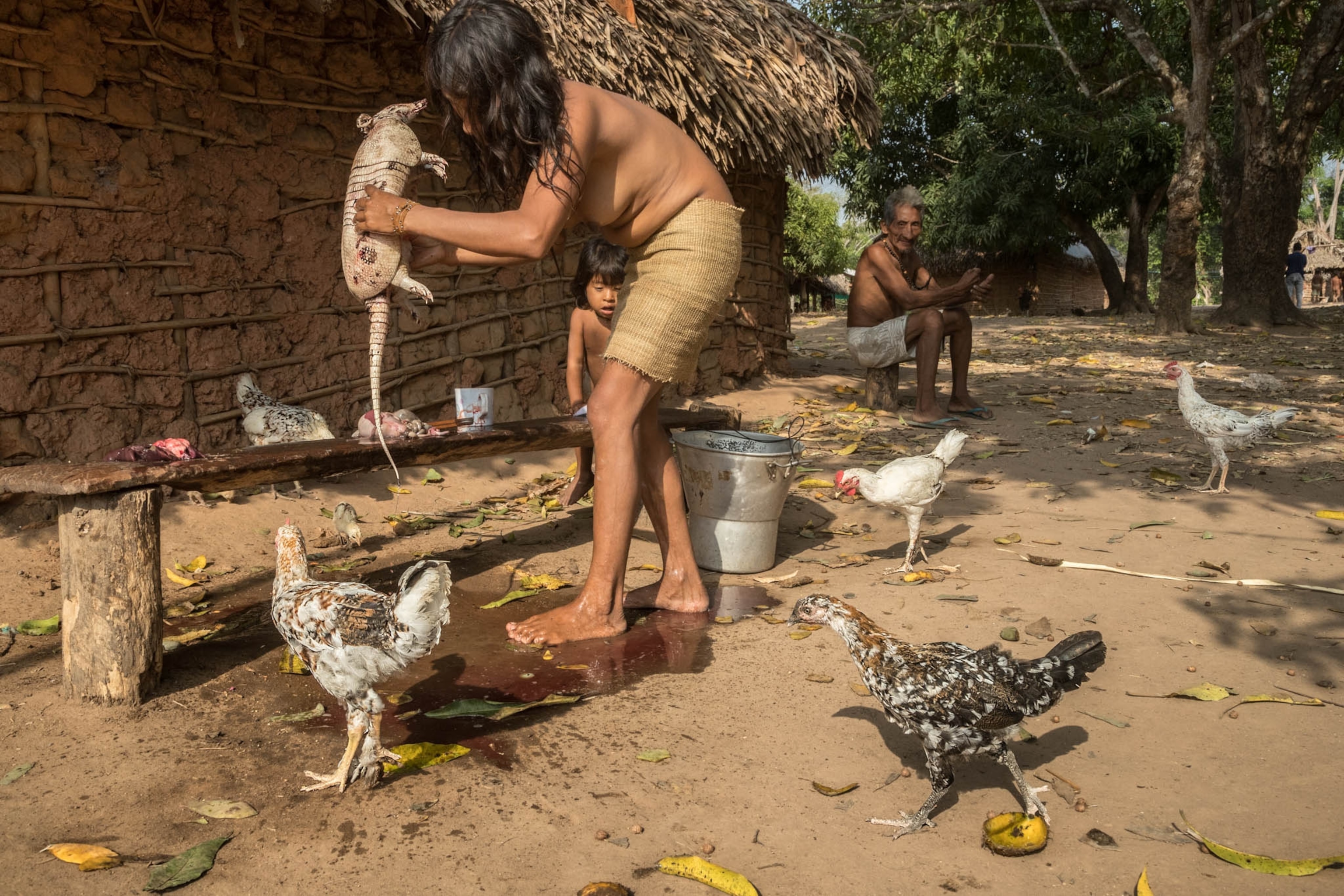 a woman butchering an armadillo on a wooden bench outside