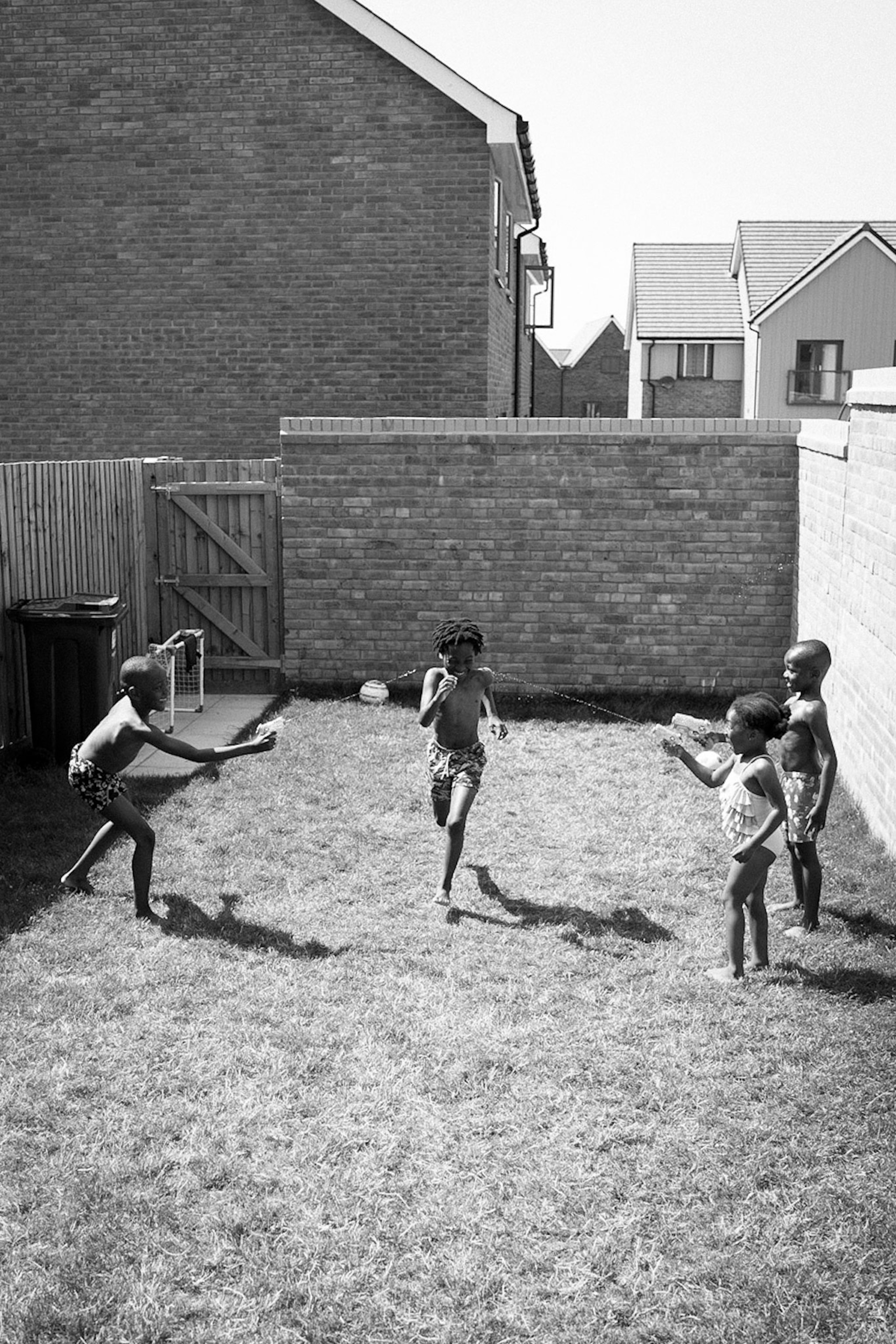 a black and white photo of three children playing in a back yard in the United Kingdom