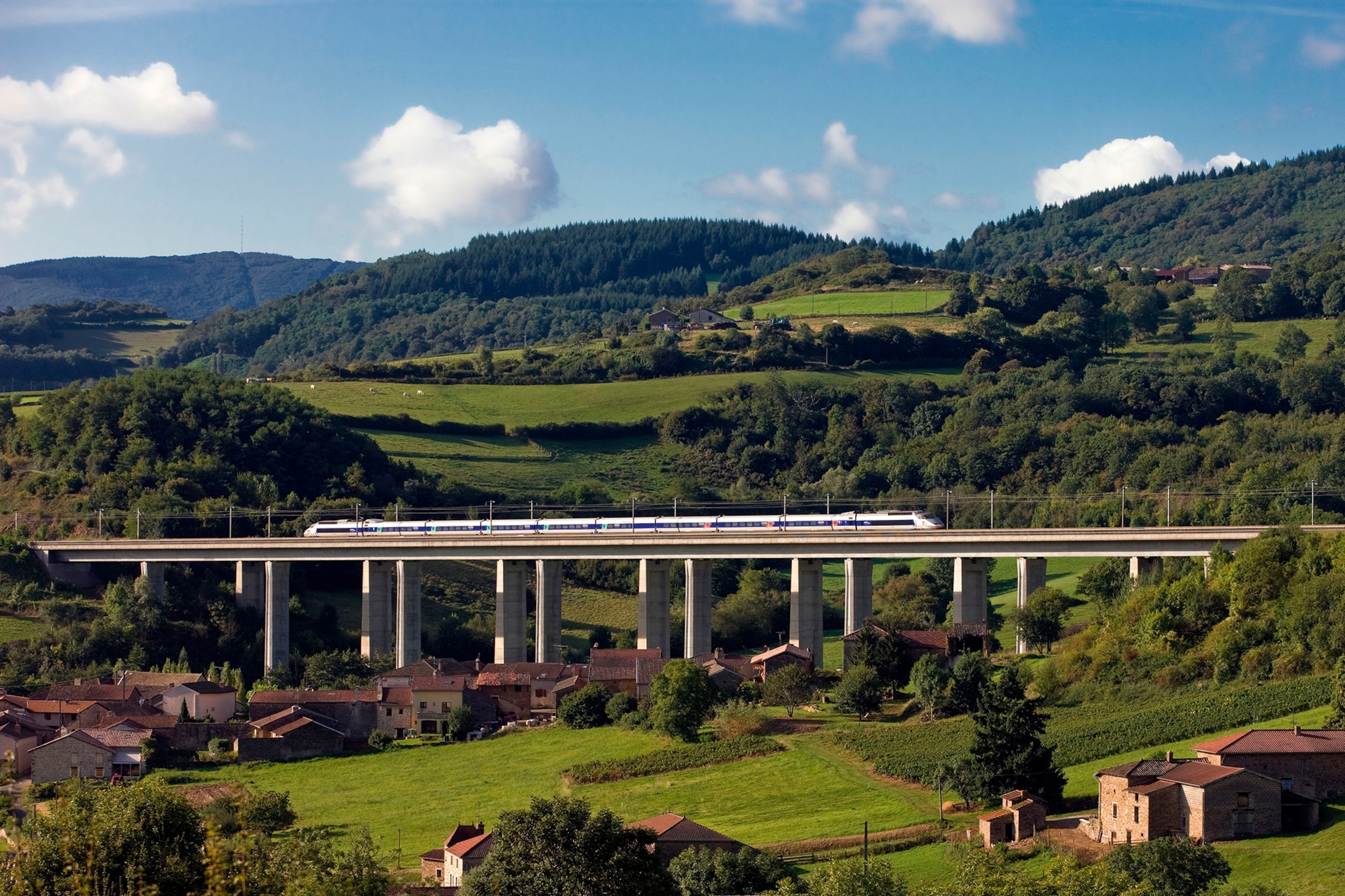 Train crossing over a raised bridge in the middle of the countryside
