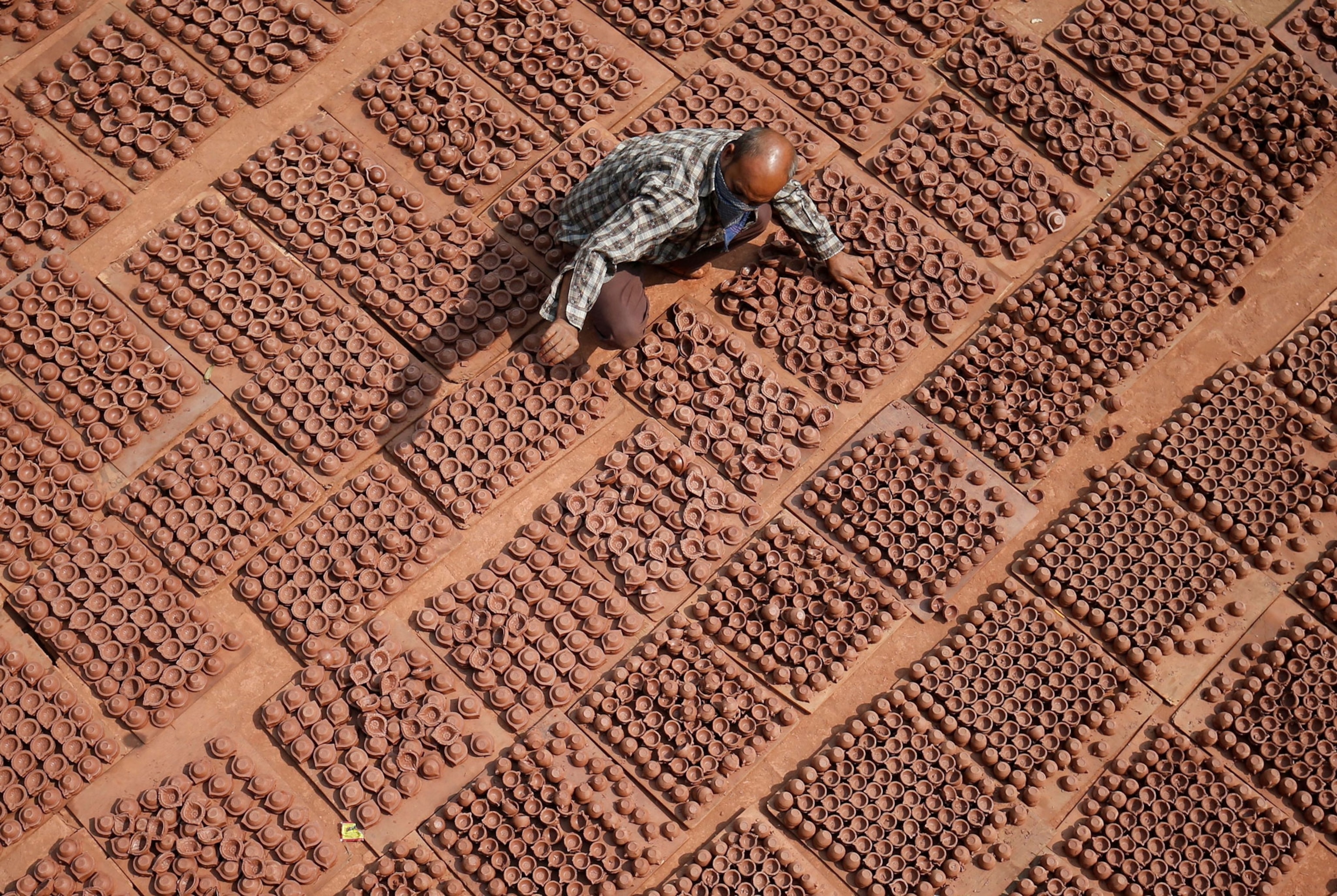 A man arranges many many small clay pots