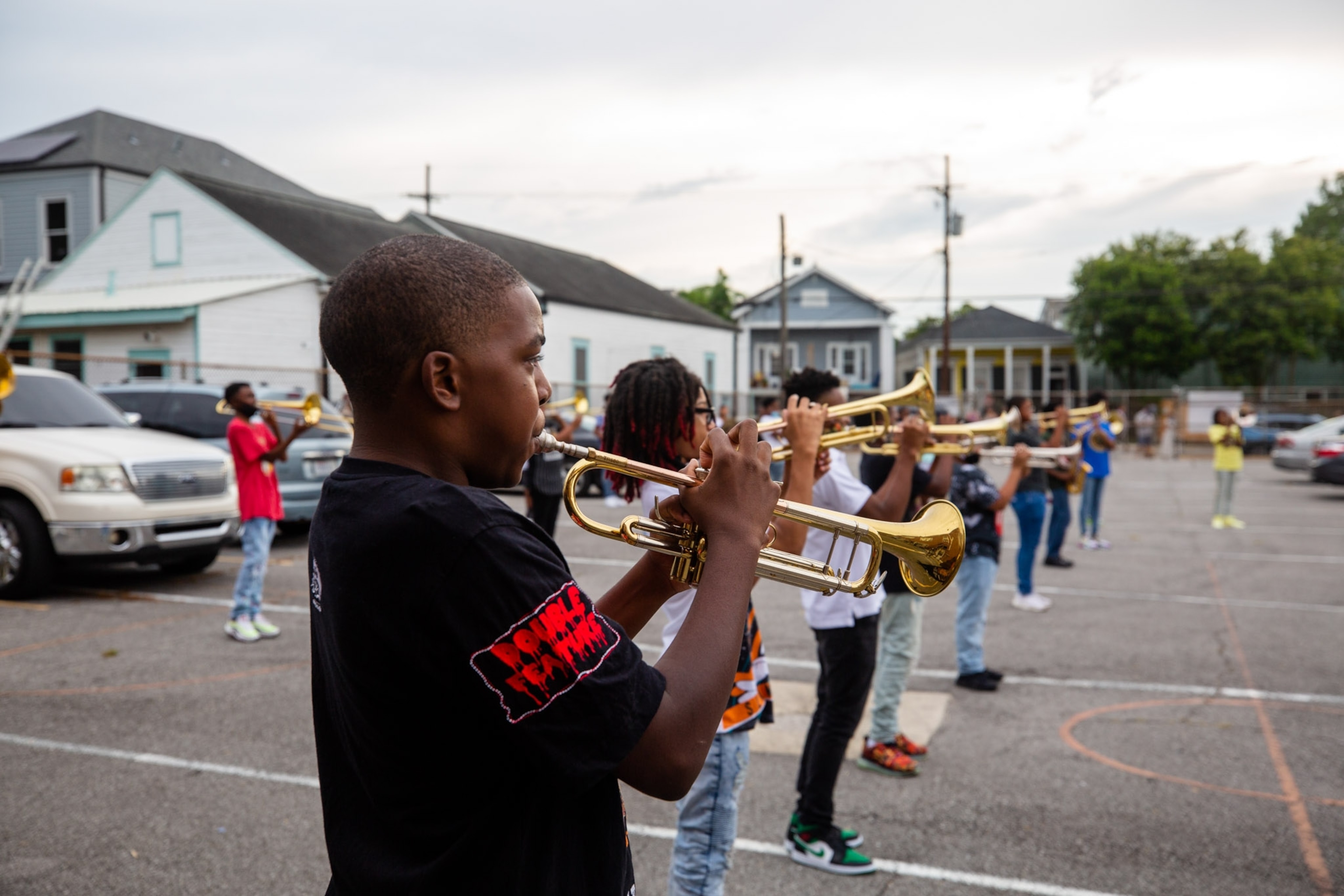a row of young adults playing trumpet in a parking lot