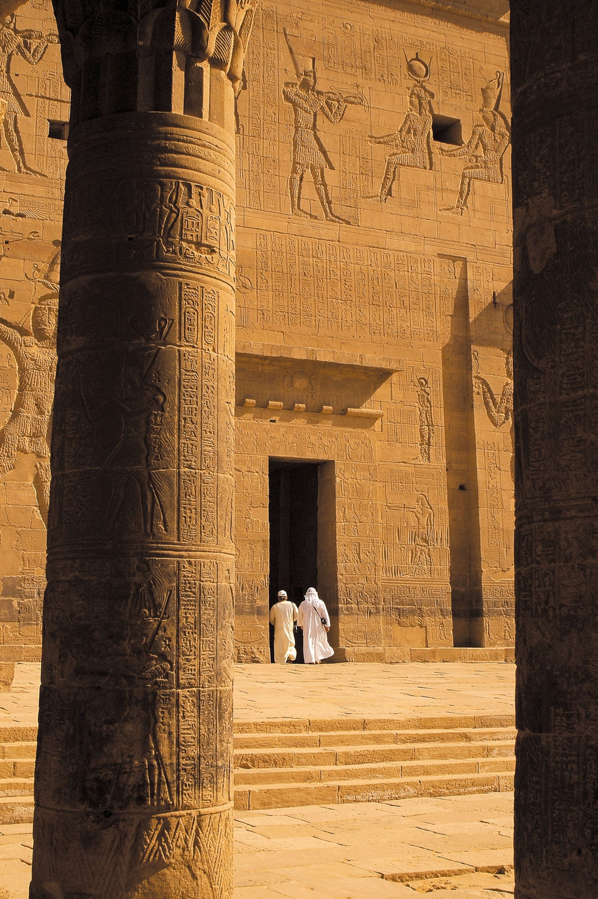 two men walking into a giant brown temple