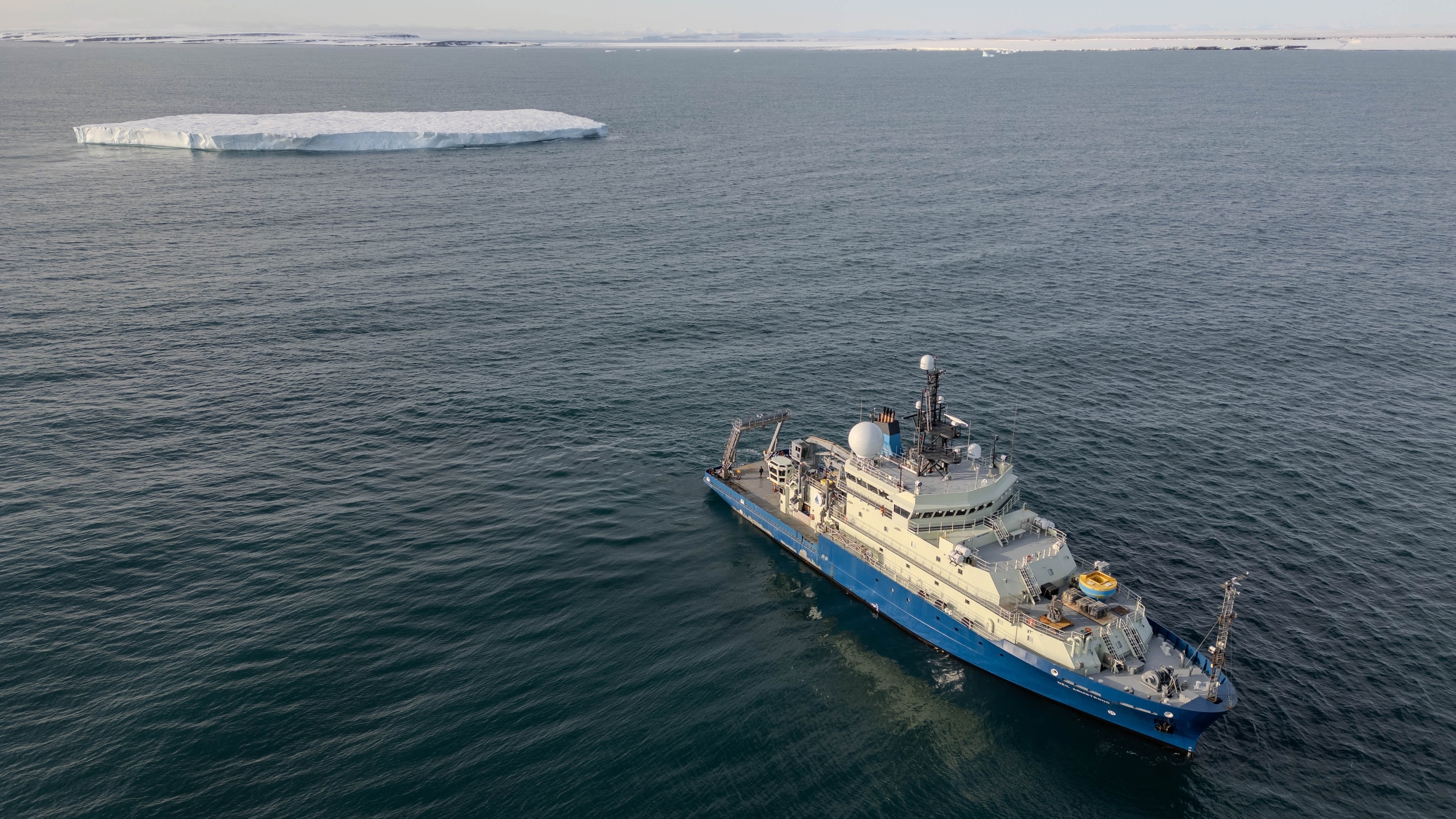 Ariel View of large ship in the open sea with a flat iceberg in background, the ship is the research vessel Neil Armstrong
