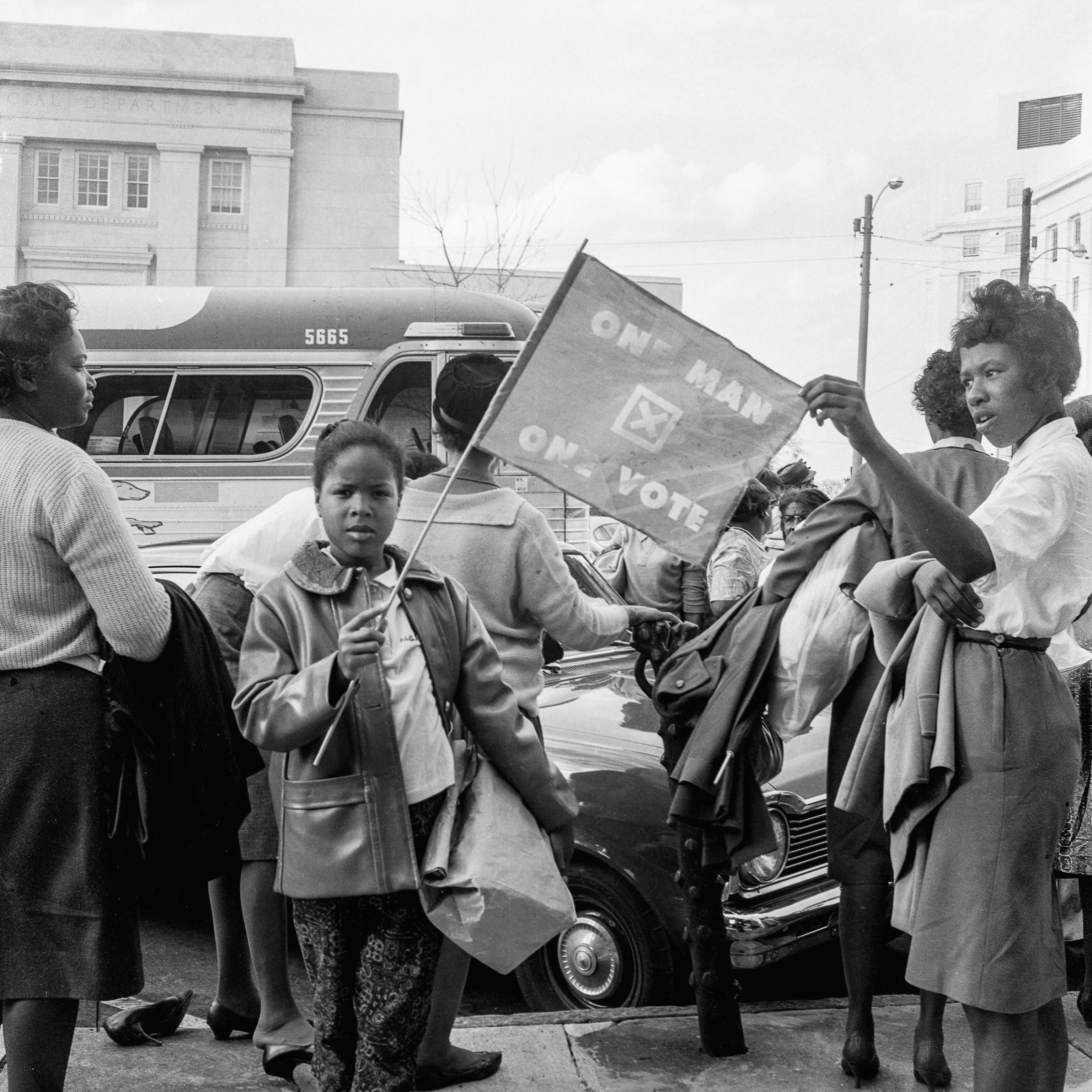 a young Black girl holding a voting rights flag