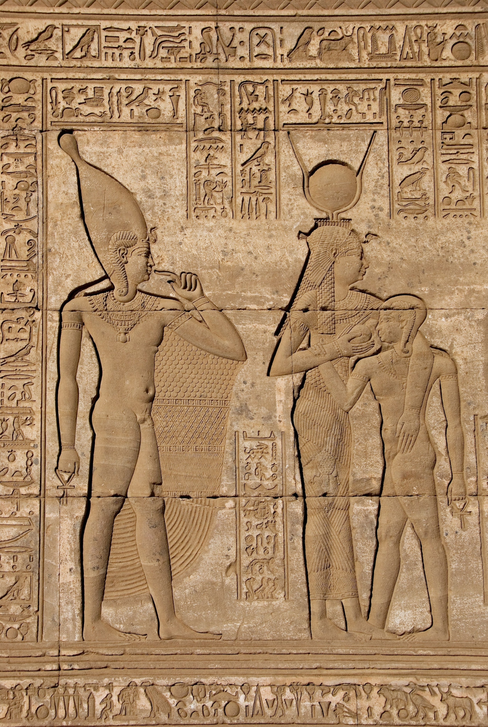 a sandstone hieroglyph of the goddess Isis, her son and the god Hathor