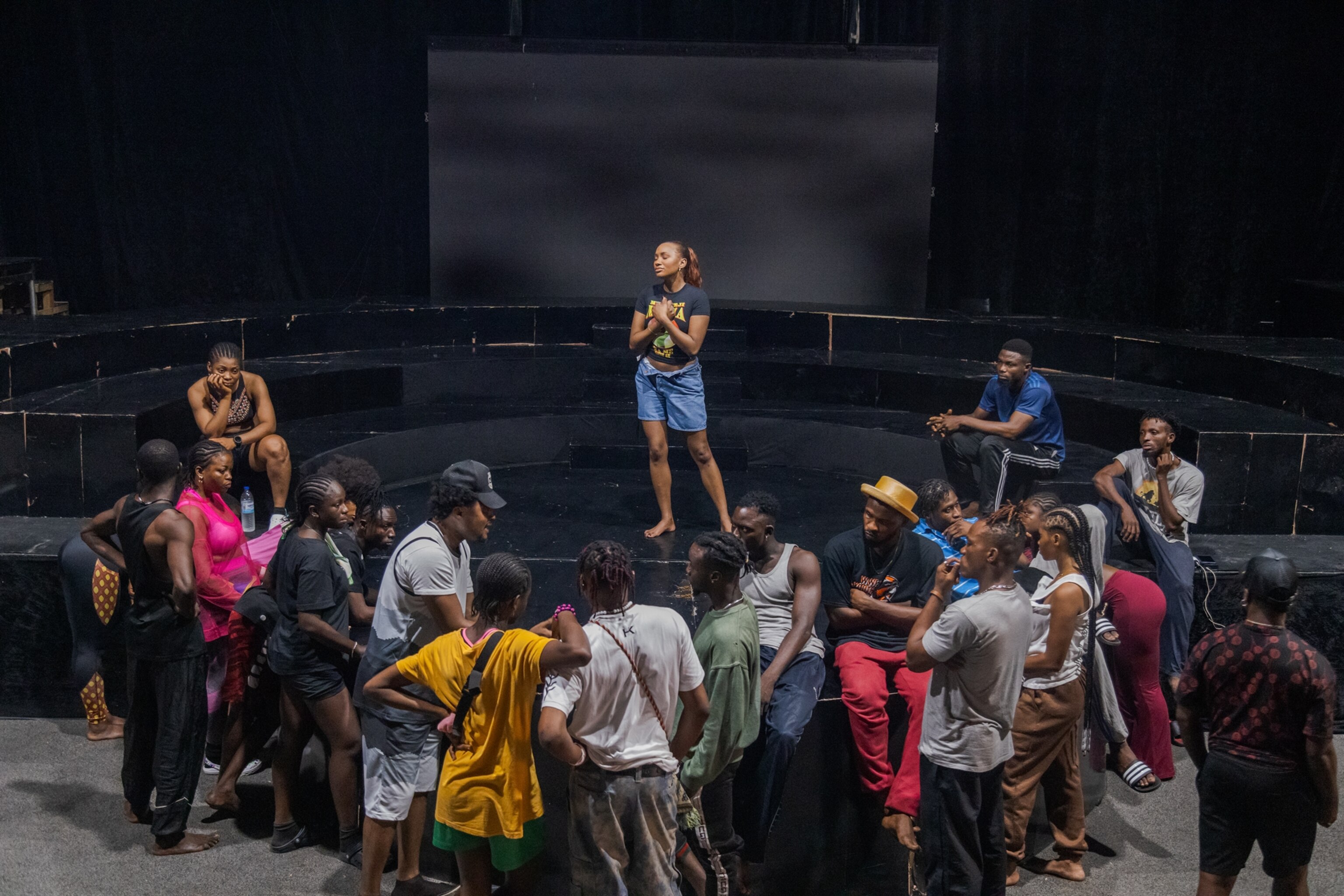 Picture of young woman on stage performing for the group of young people.