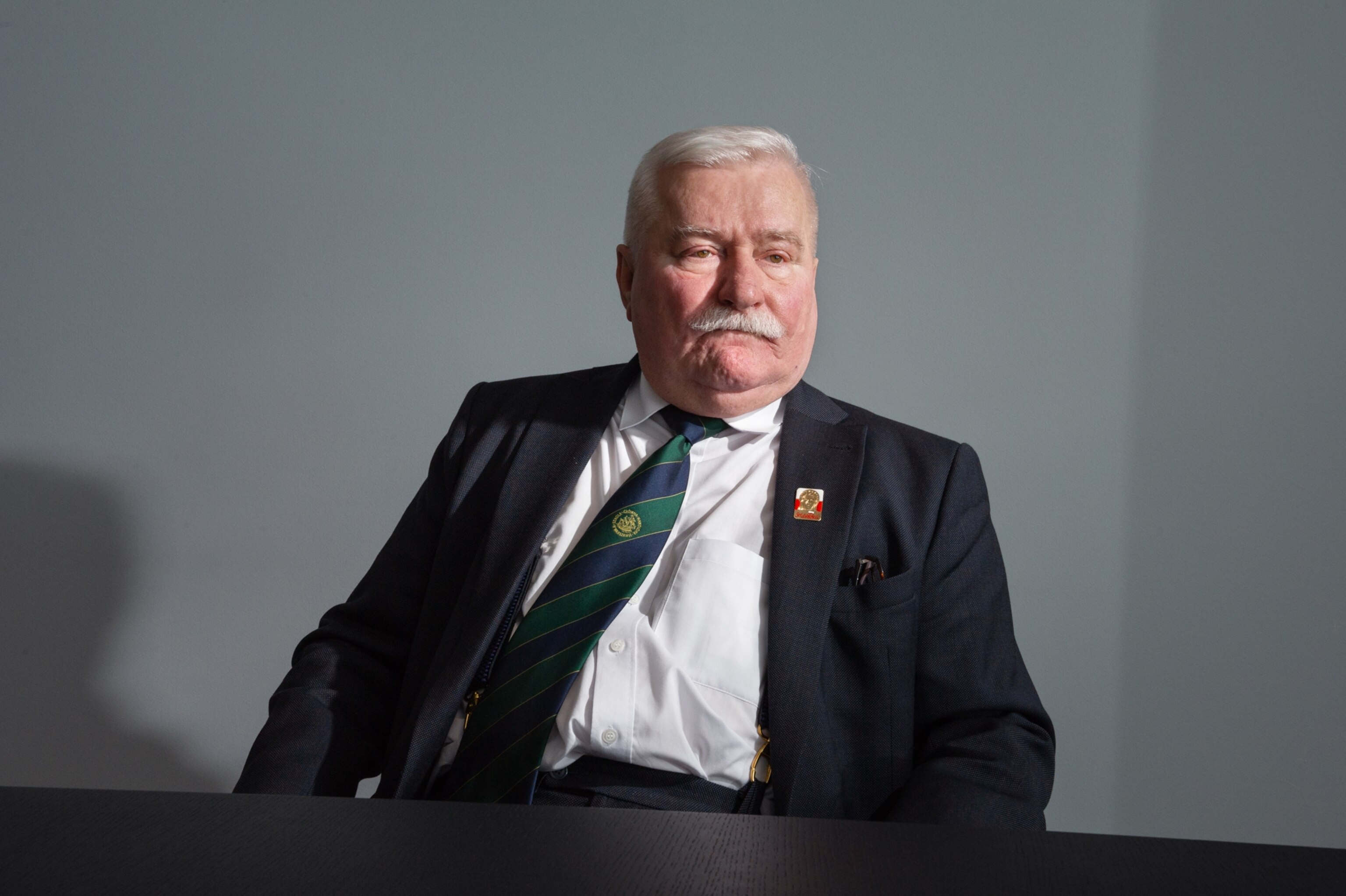 a man sitting at a table, wearing a suit