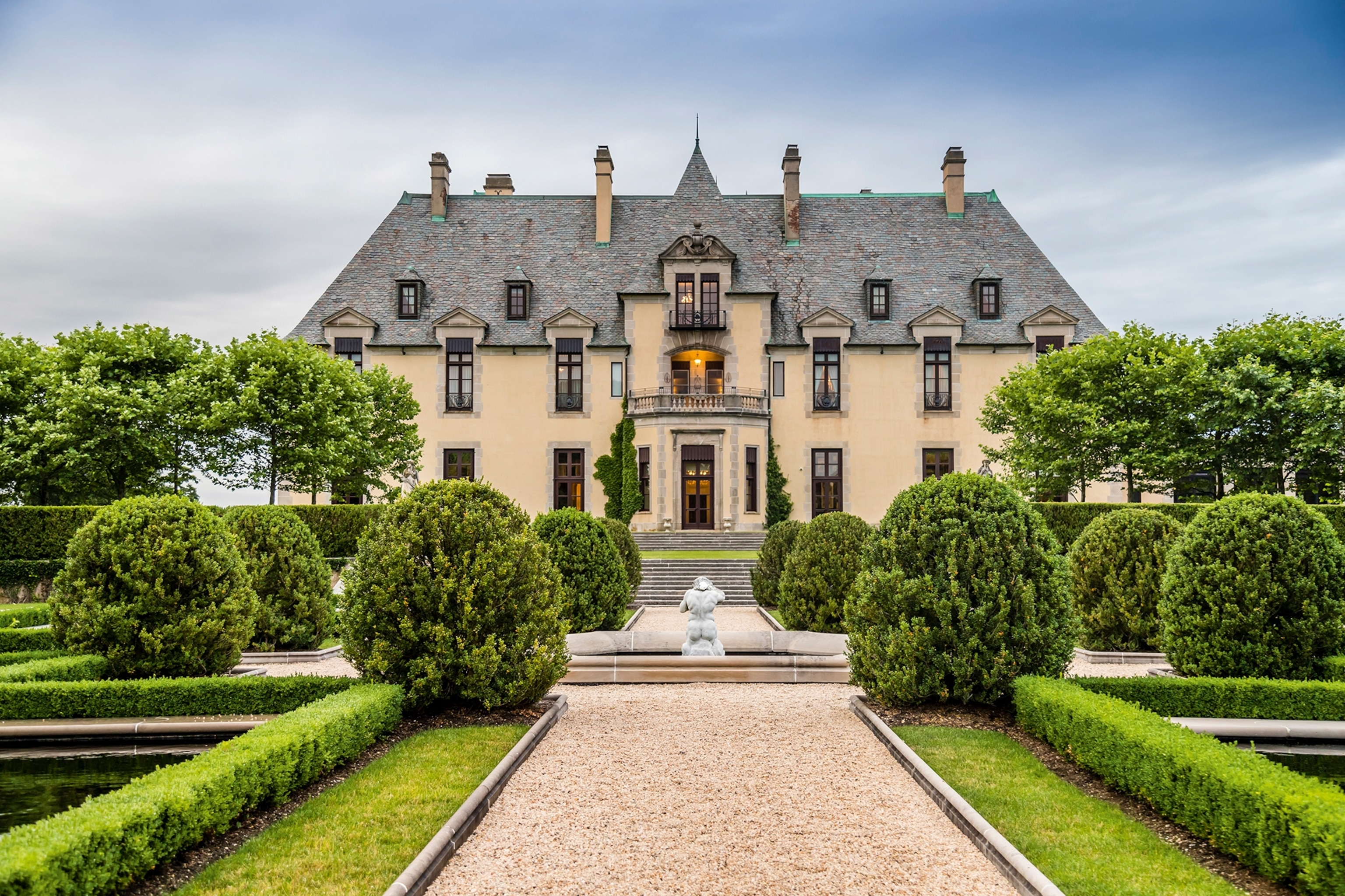 An impressive mansion with a curated gravel garden and a fountain in the middle.