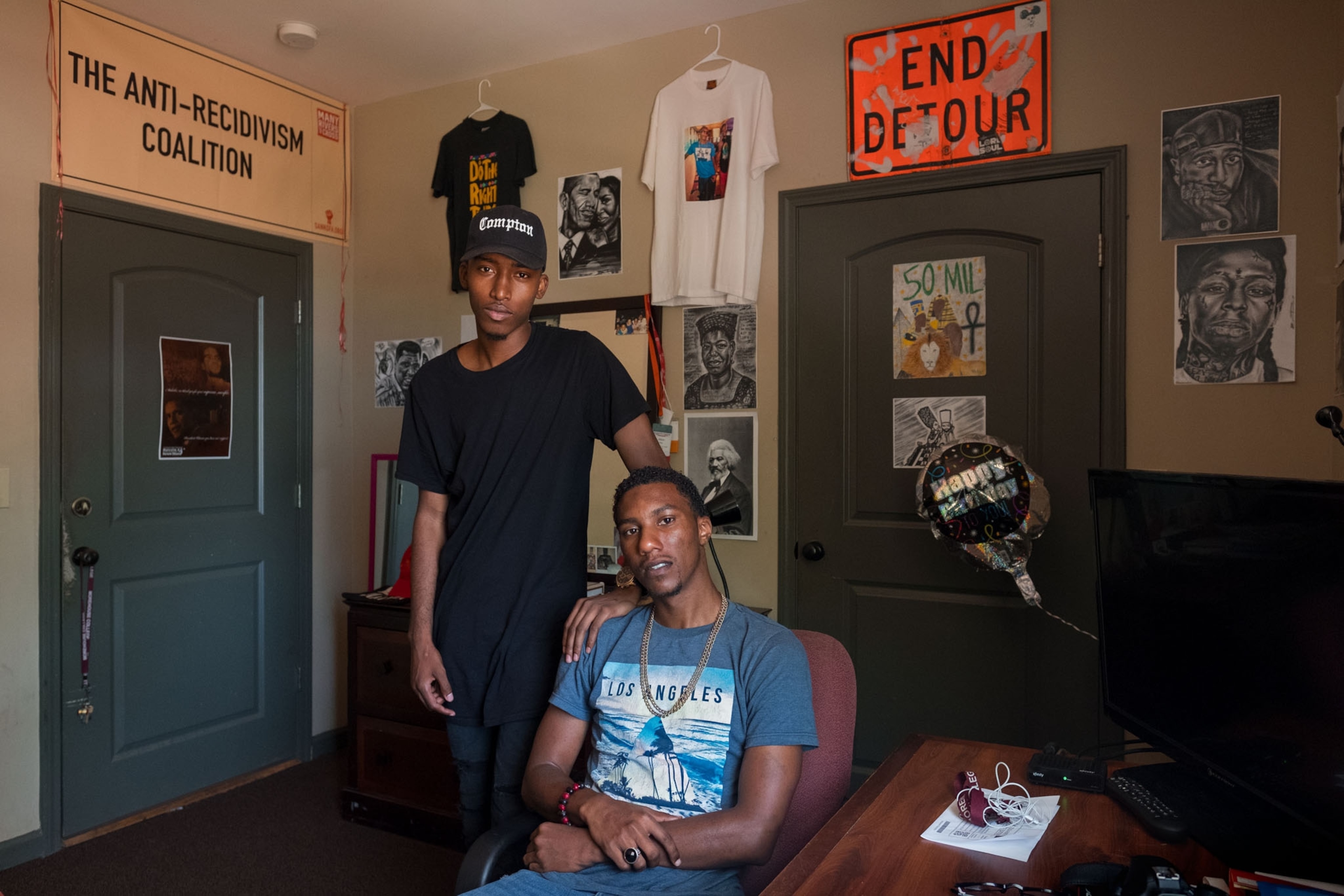 two young black students posing for a portrait in their dorm room