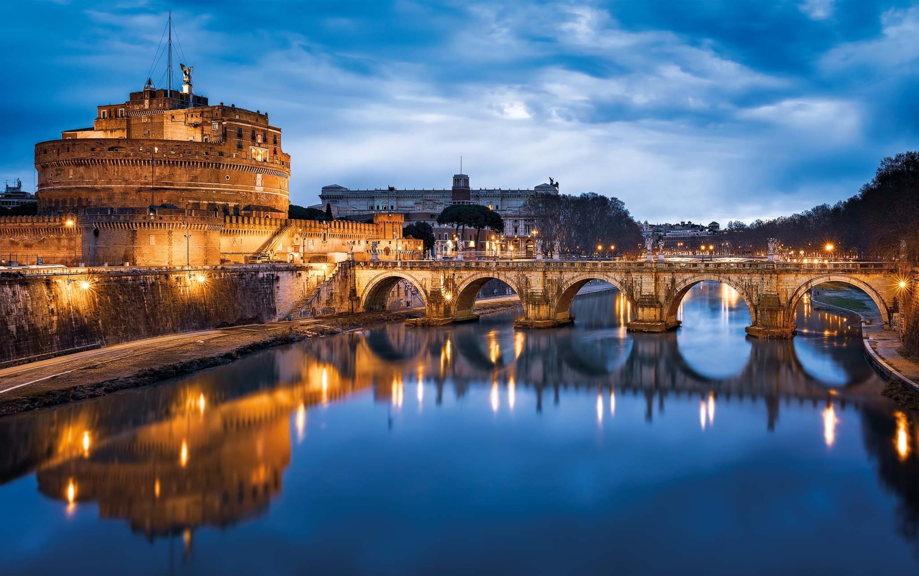 A view of Rome's Mausoleum of Hadrian, the bridge before it, and the river at night