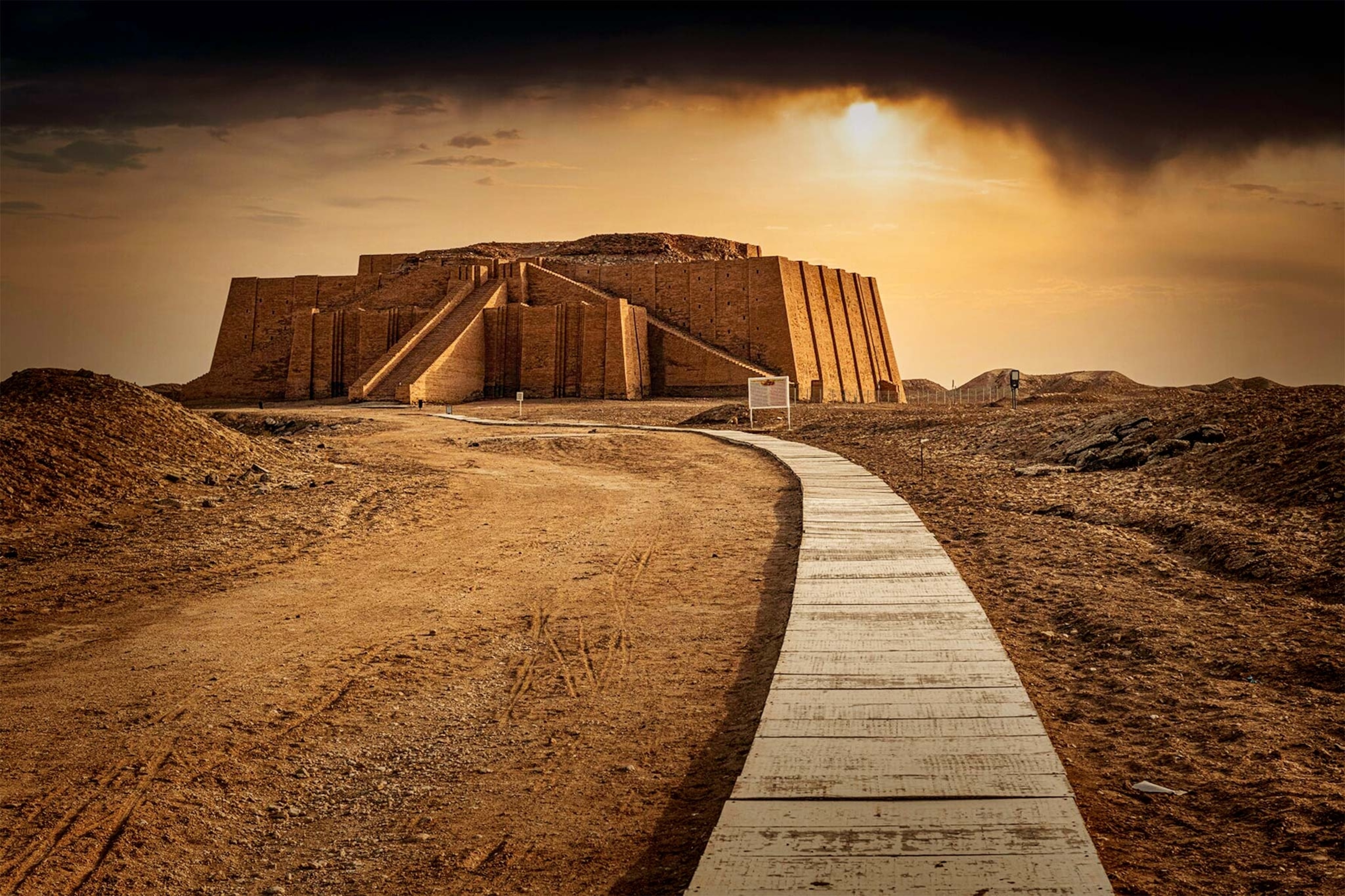 Ziggurat of Ur sits atop a small hill with the sun behind it