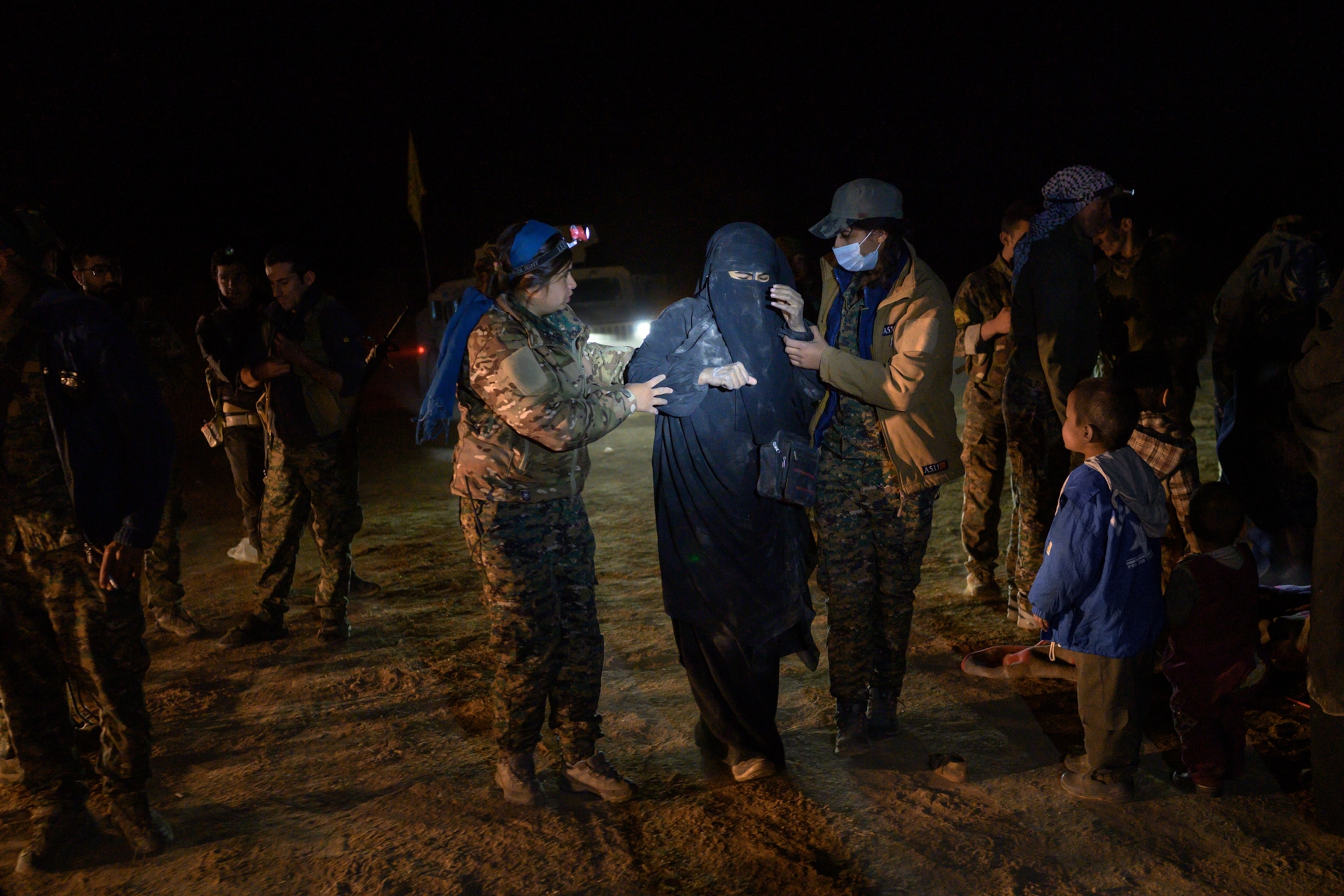 two woman walking a alongside a surrendered ISIS sympathizer