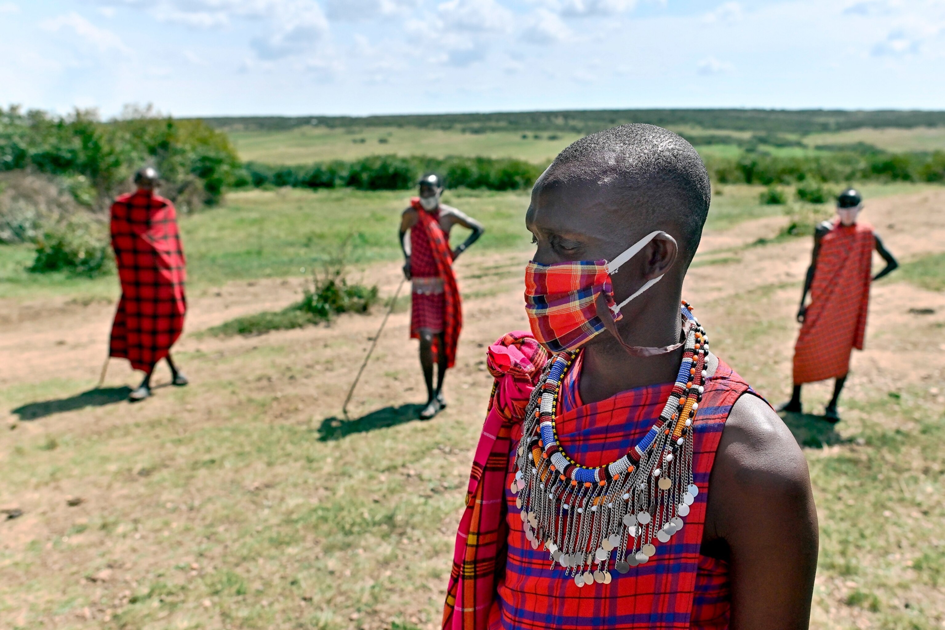 members from the Maasai tribe wear cloth masks in Kenya’s Maasai Mara National Reserve