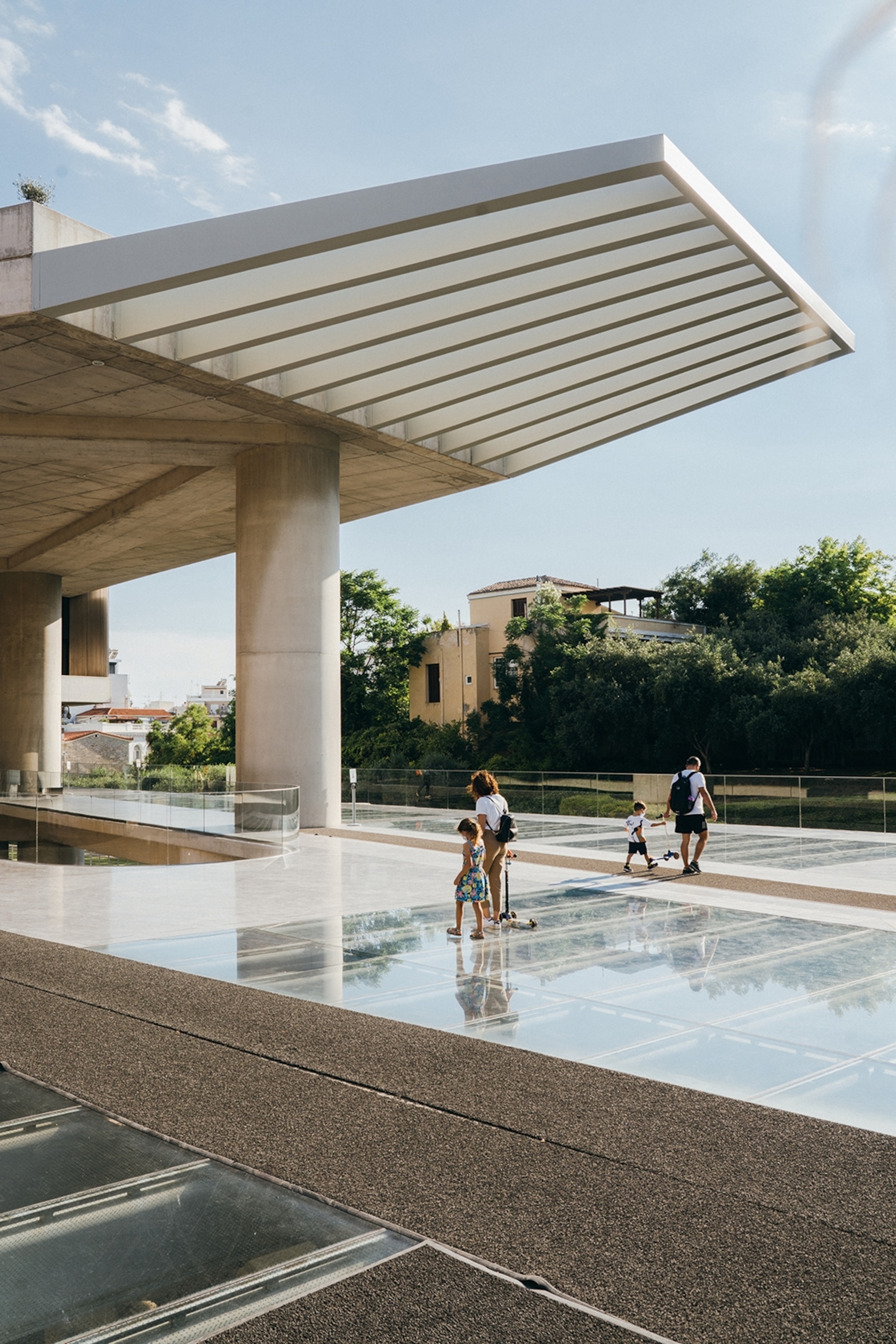 People walk upon a glass balcony surrounded by modern architecture