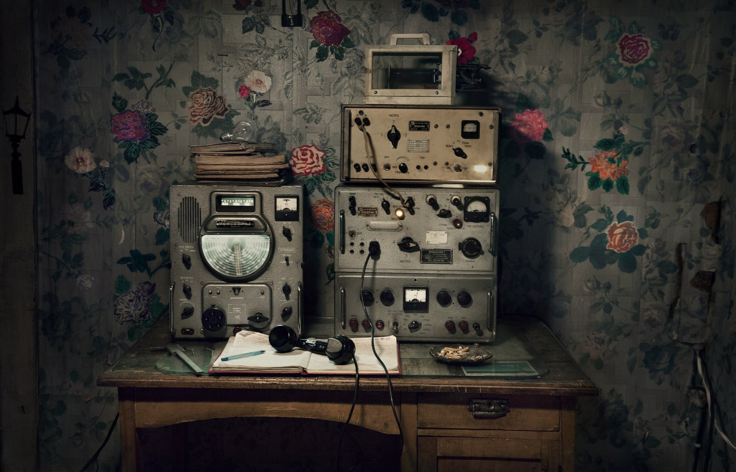 old radio on the desk against the wallpaper with flowers on it.