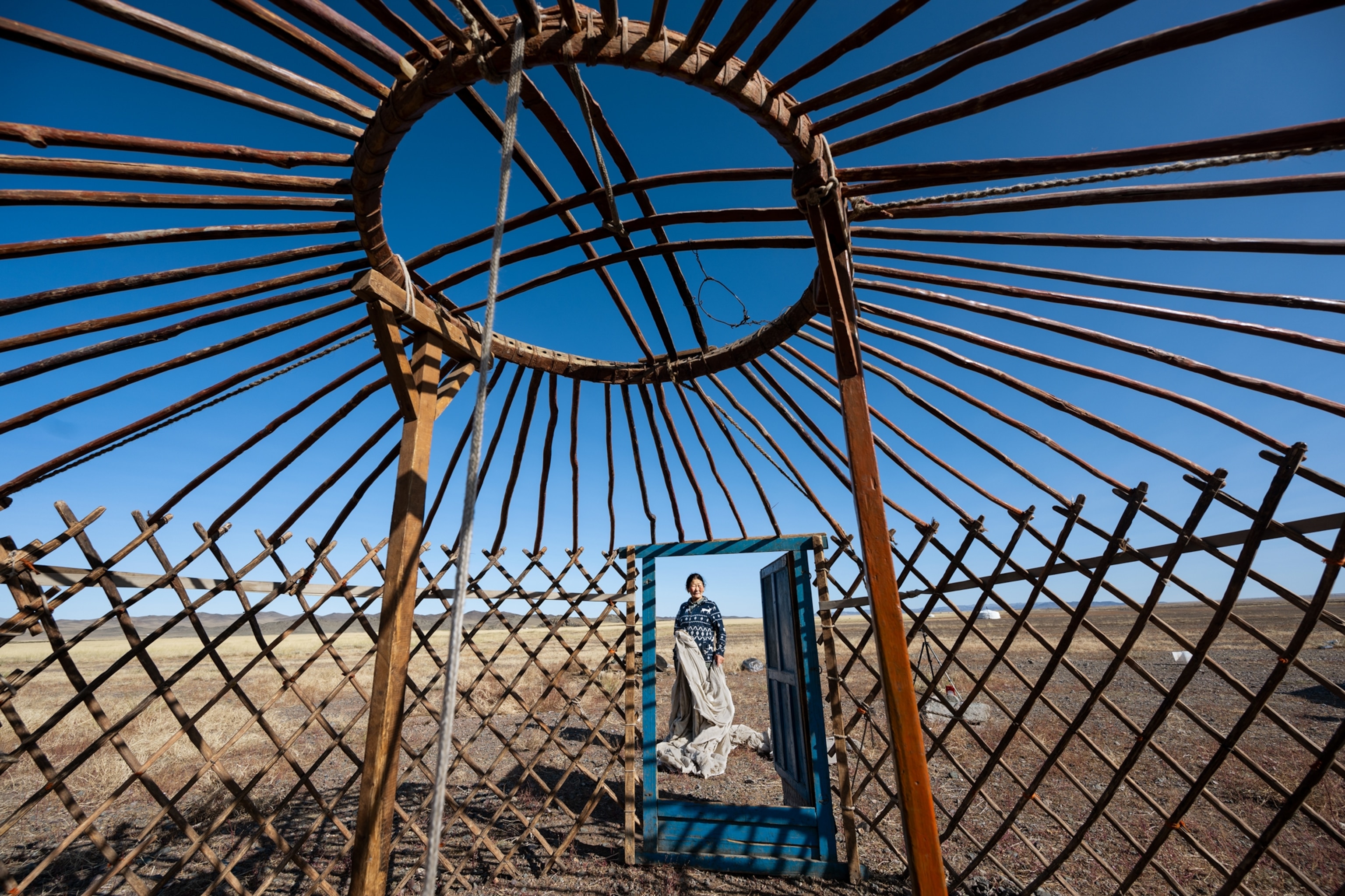 Herder Tumen Ulzii carries the felt and canvas covering to set up a ger. The ger is a round structure of walls, poles and a peaked roof.