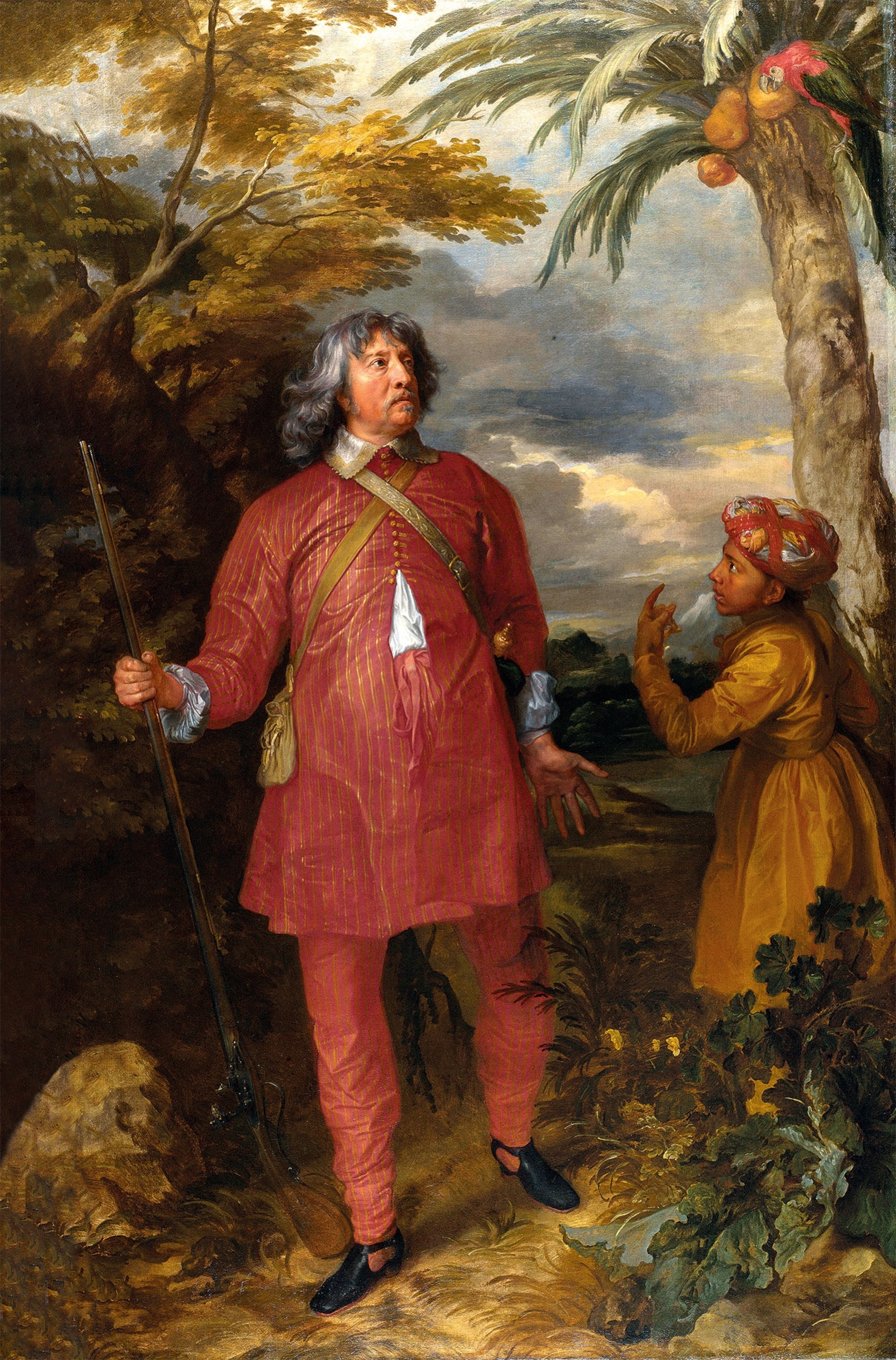 A man with long grey hair holds a rifle wearing a red kurta pajama next to a boy in an orange set