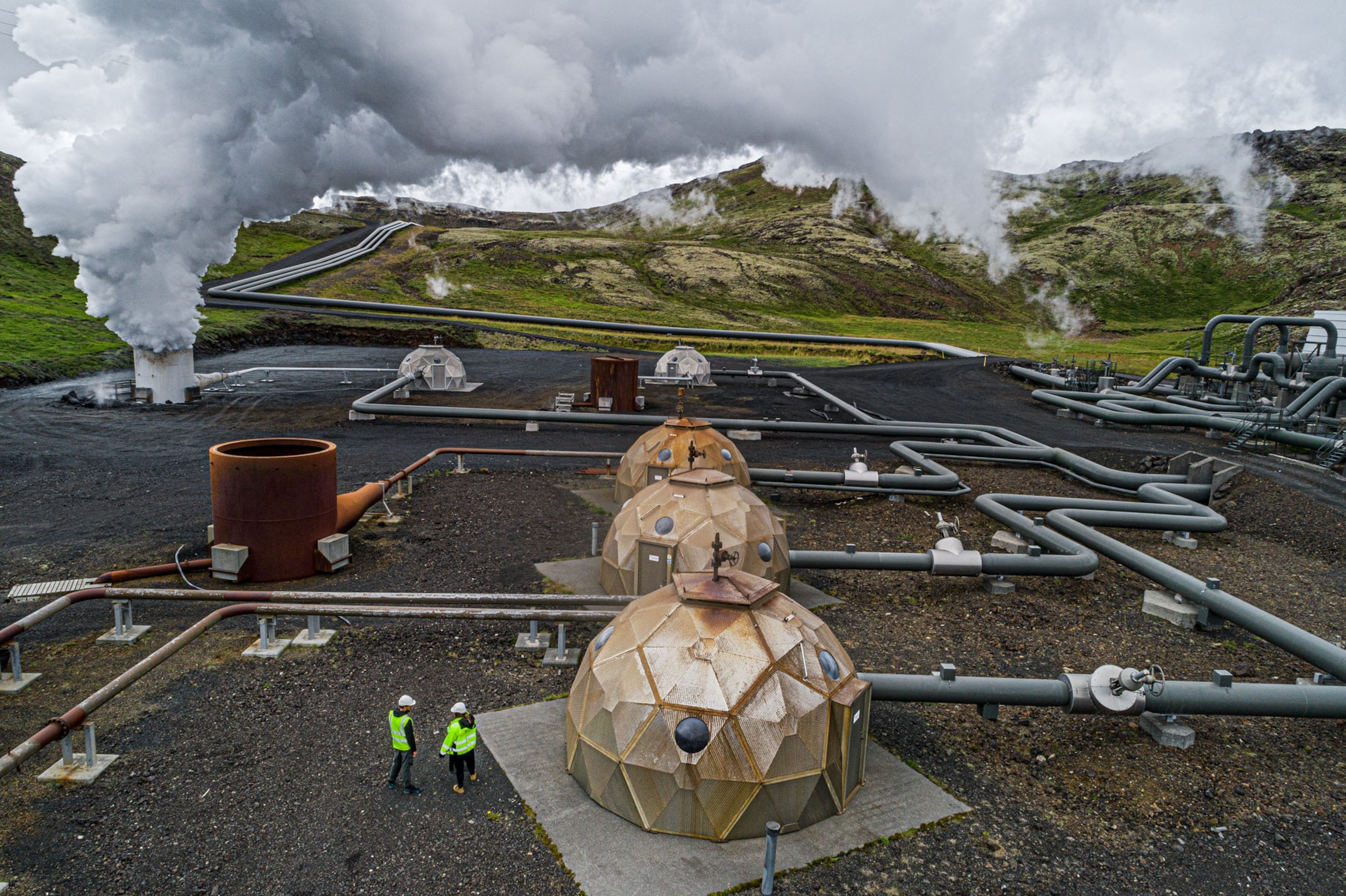 two people outside at a working energy plant with several domes