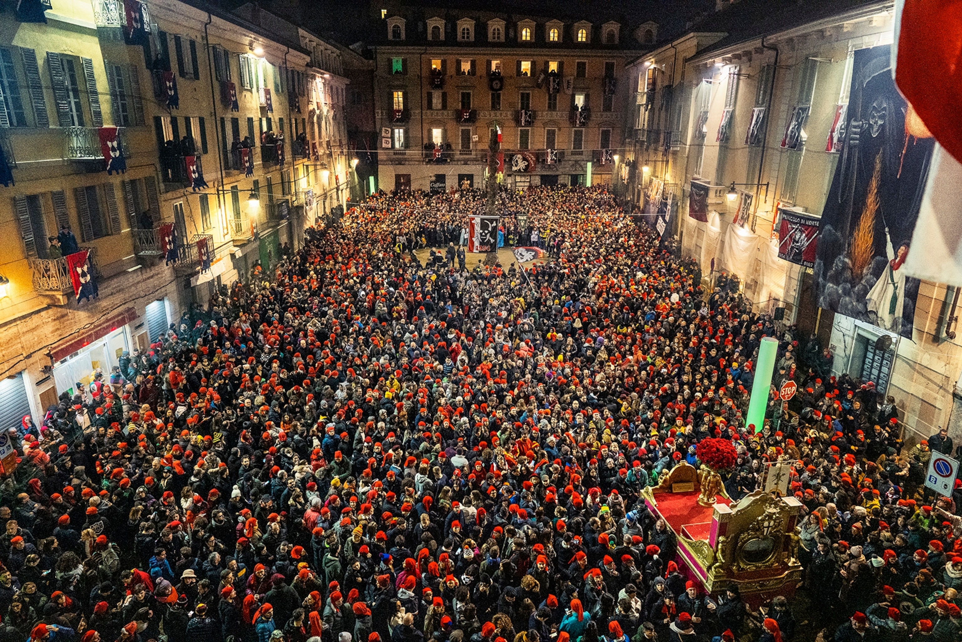 Piazza di Città, Ivrea's main square is packed with people waiting for the ceremony of the burning of the Scarli (bonfires of poles covered with heather and juniper). This is one of the rituals that concludes the city's long celebration of carnival.