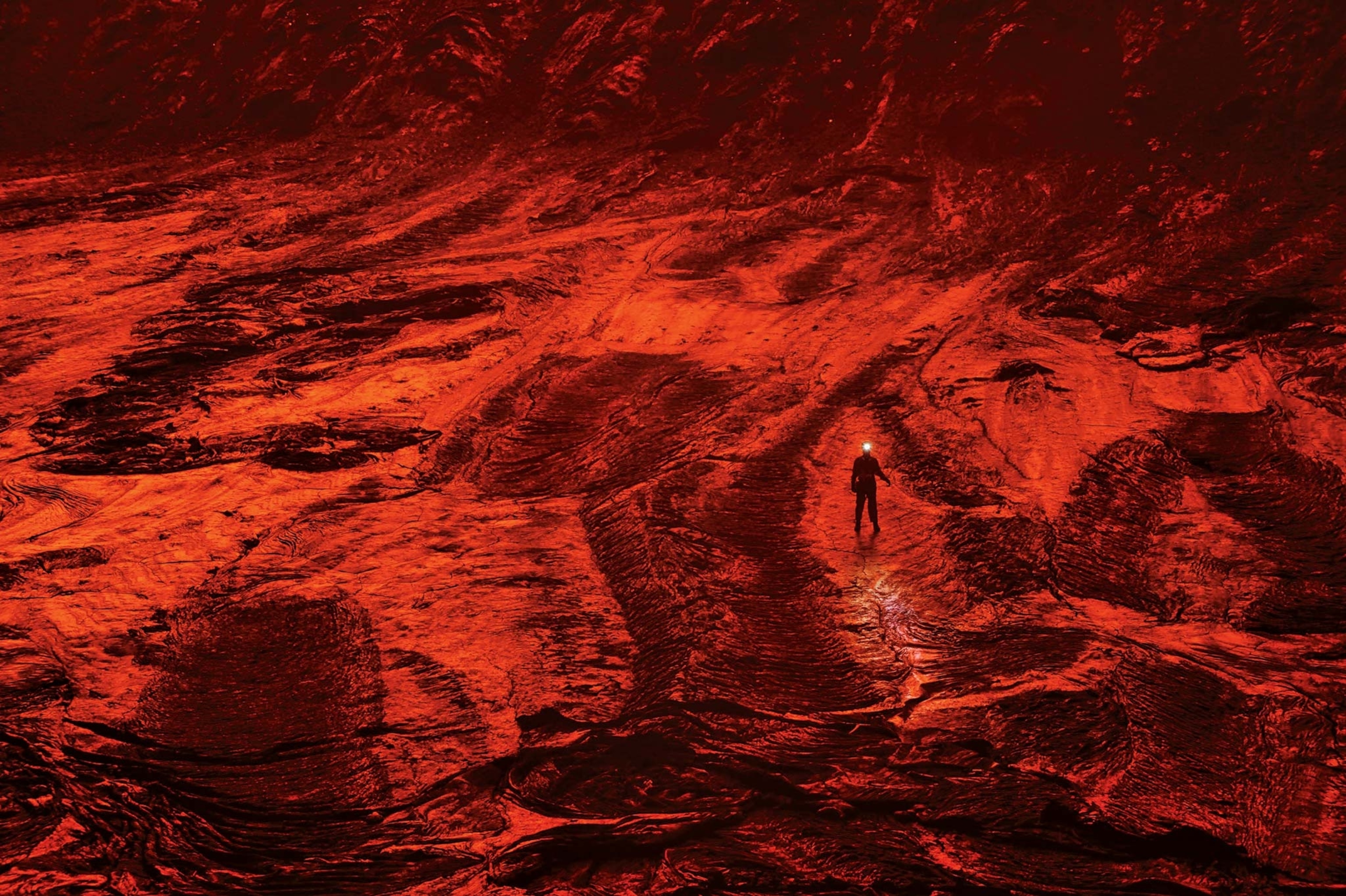 A scientist walks on the cooled lava floor of a volcano