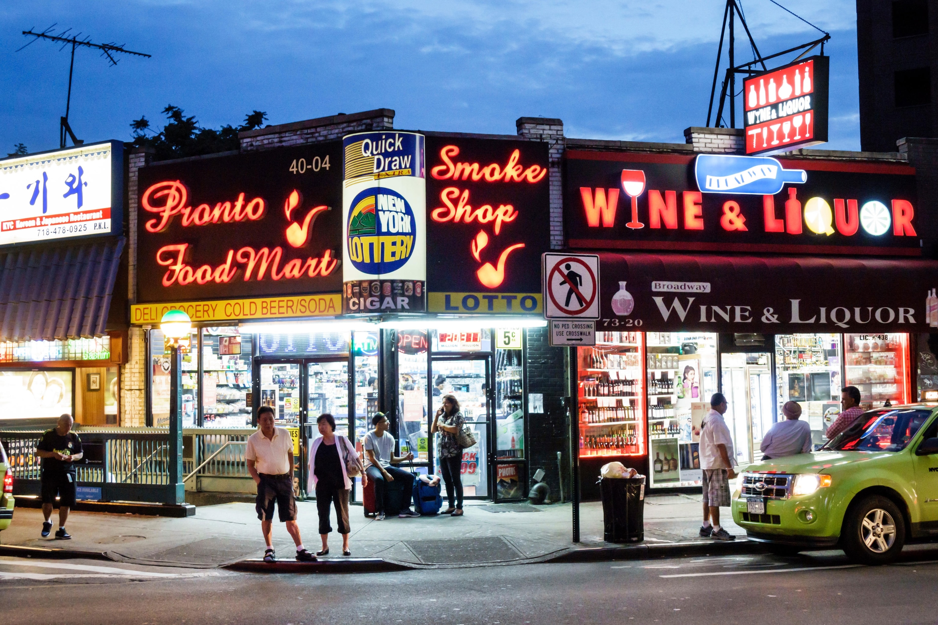 corner of walkway in the evening with neon signs for corner shops