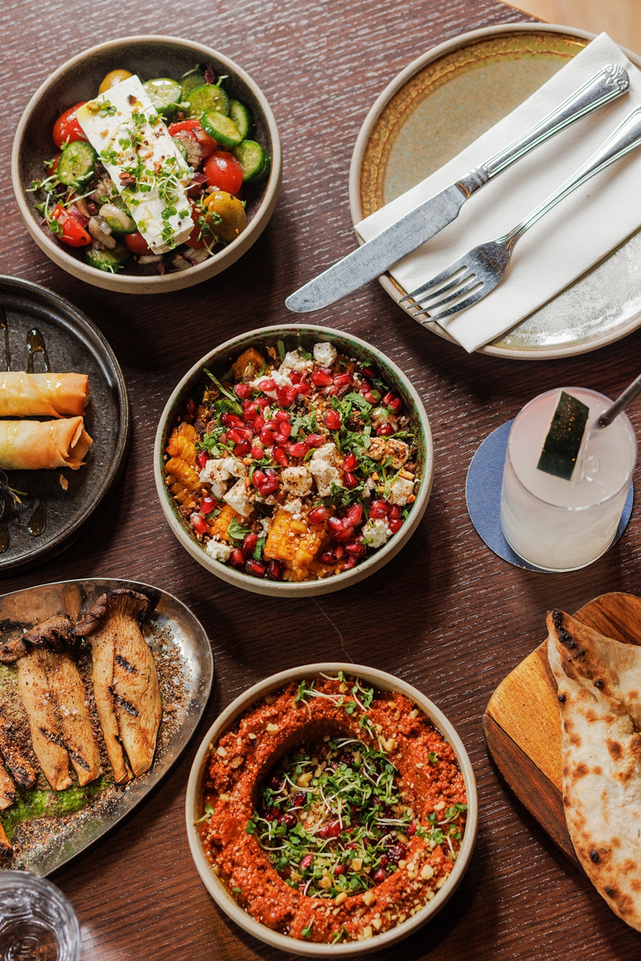 A table spread with a variety of different Mediterranean dishes including naan bread and corn ribs.