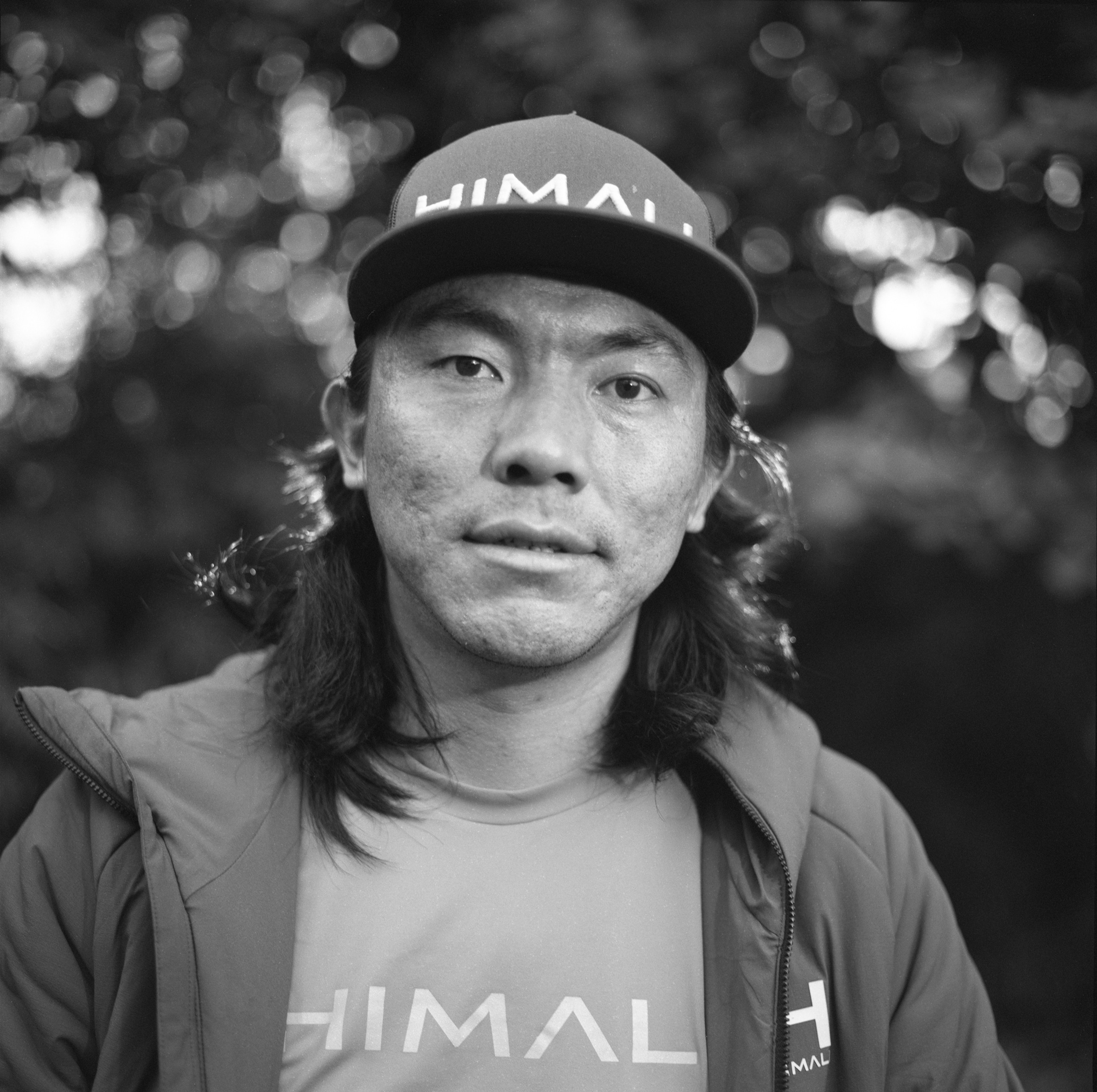 Picture of black-and-white portrait of a man with long hair under baseball cap.