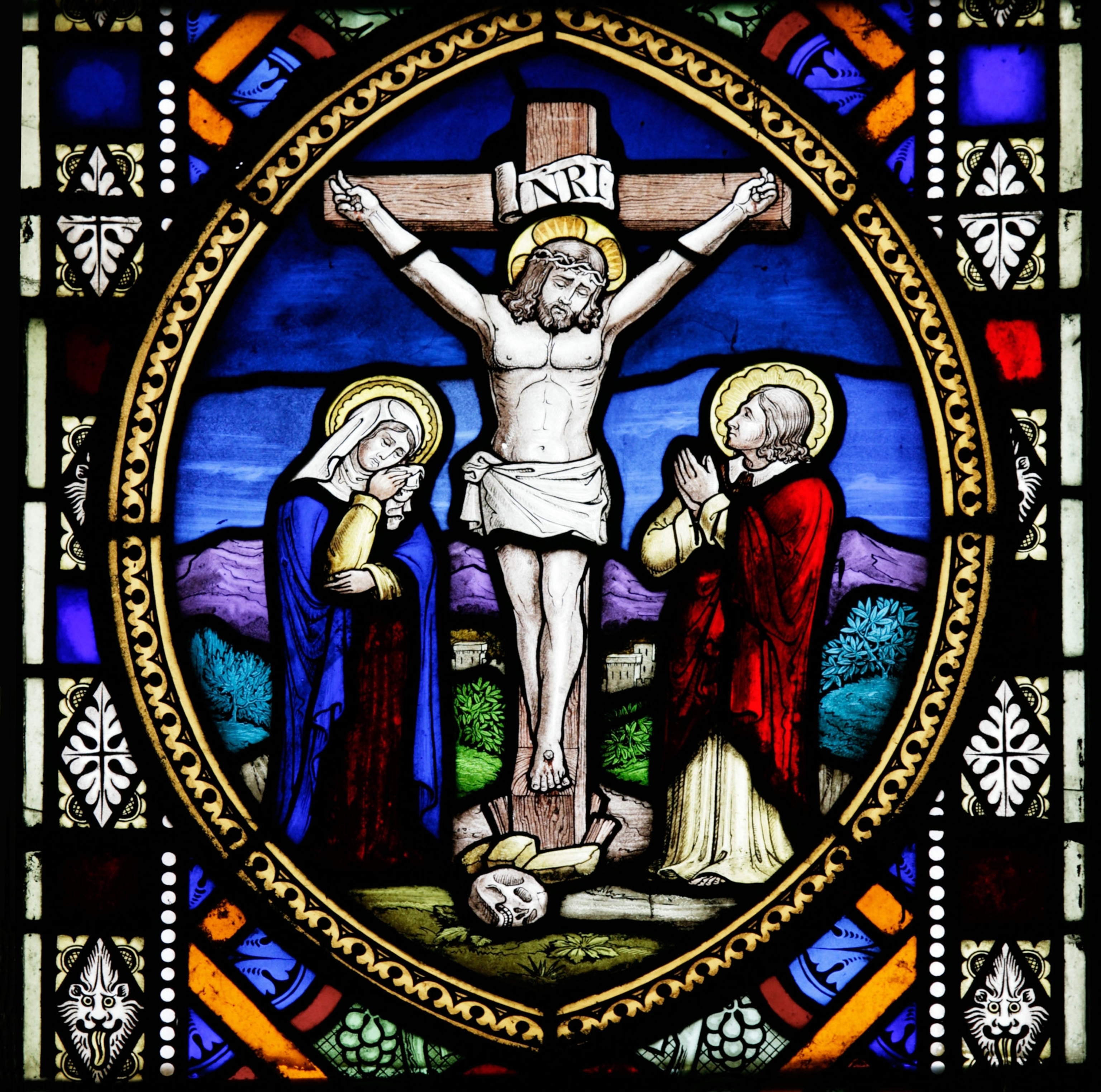 Detailed and colorful stained glass window depicting the Crucifixion of Jesus Christ in the Church of St Andrew and St Mary, Langham, Norfolk.