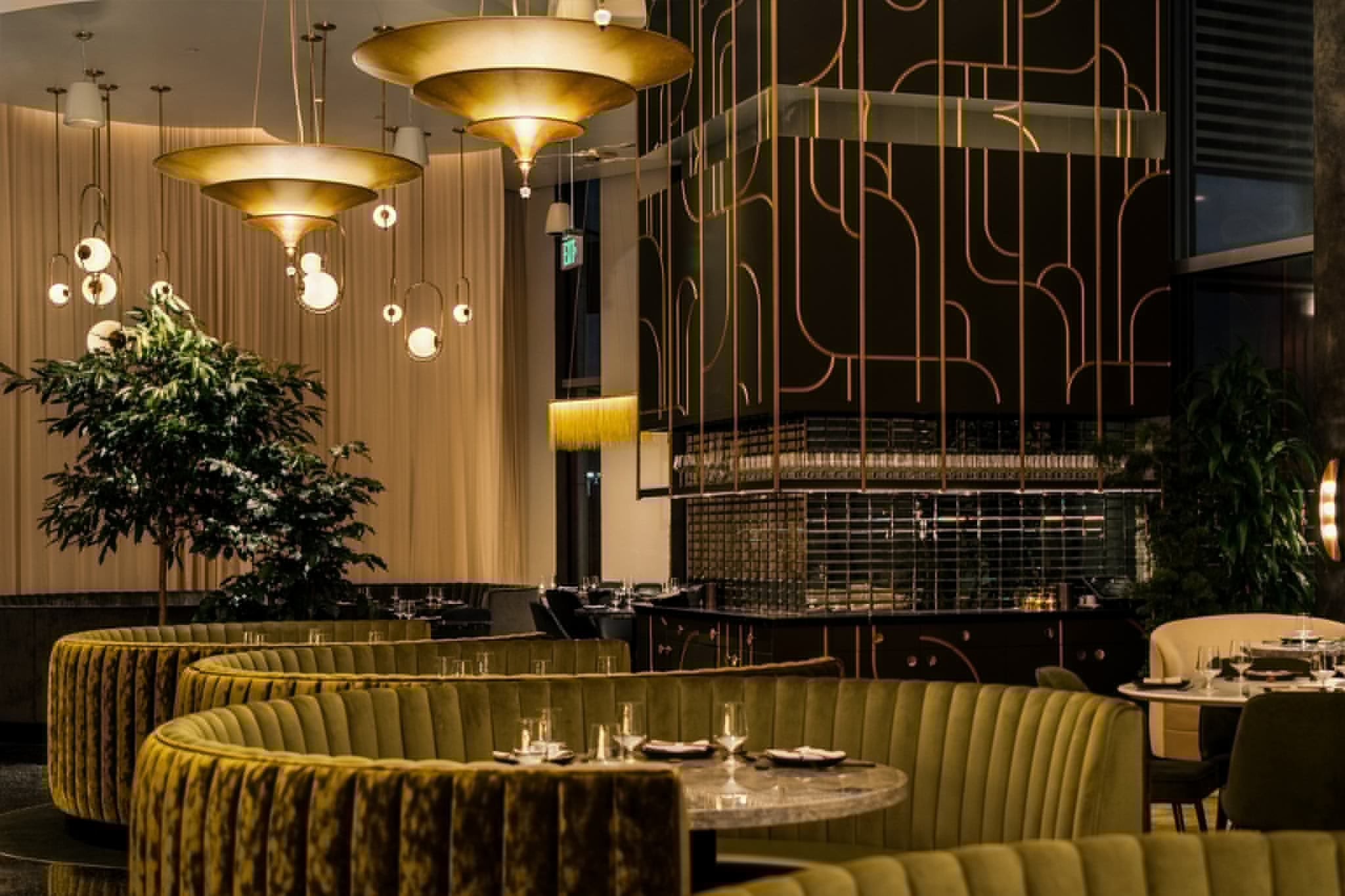 Green velvet seating and gold lighting center the elegant decor at Animae Restaurant in San Diego.