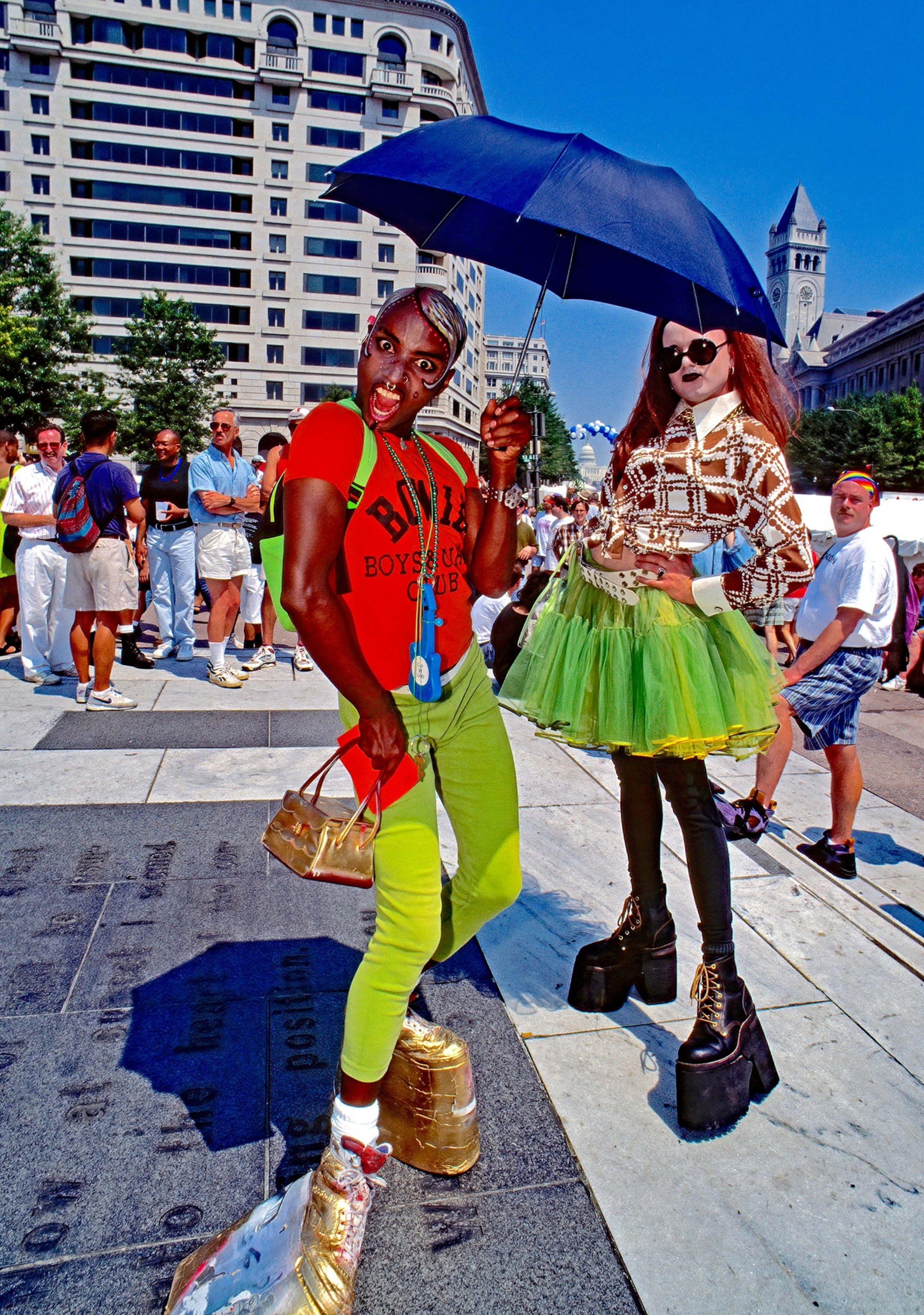 Two people stand together with brightly colored clothing.