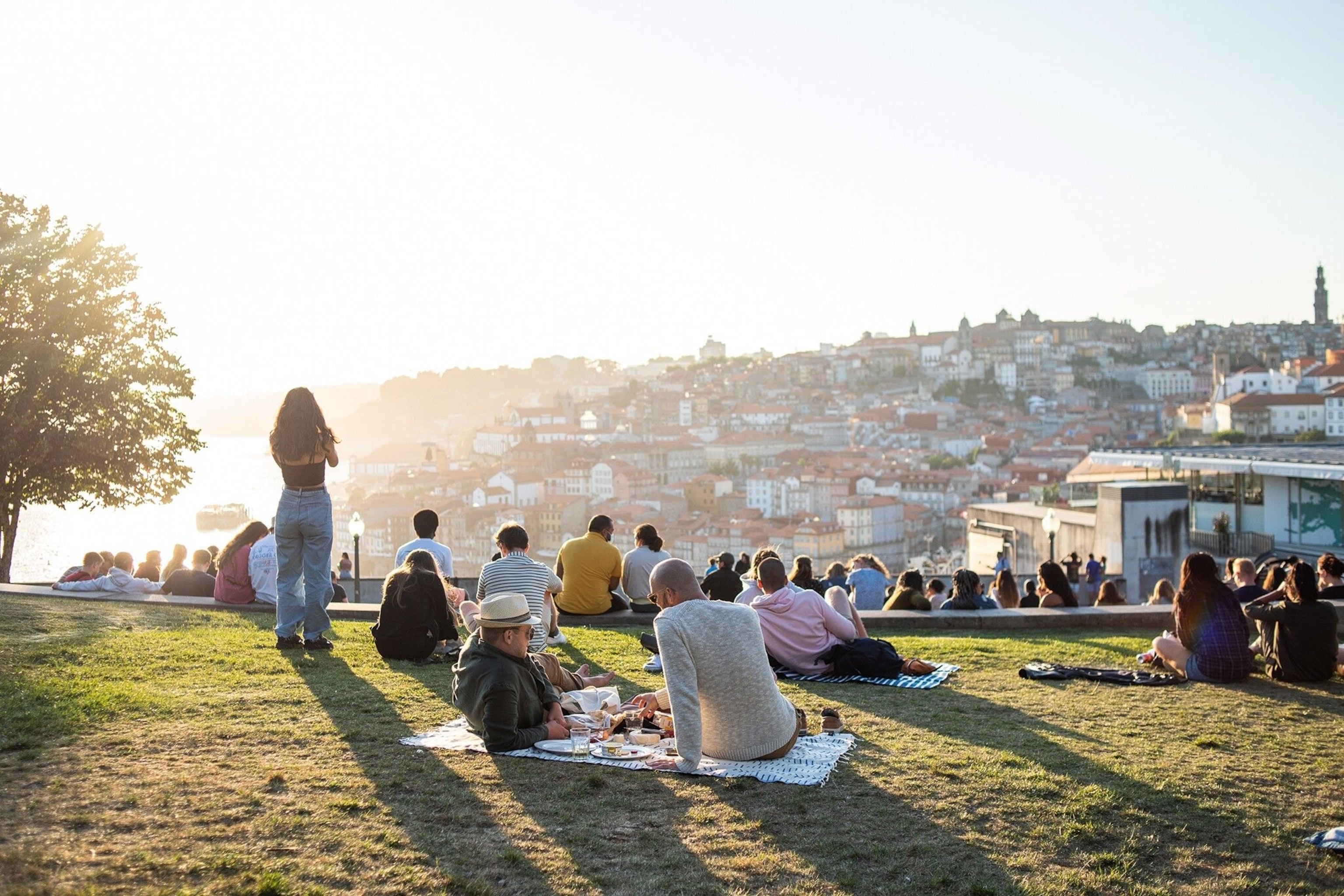 People sitting and enjoying the viewpoint at Jardim do Morro, overlooking Porto's historic buildings.