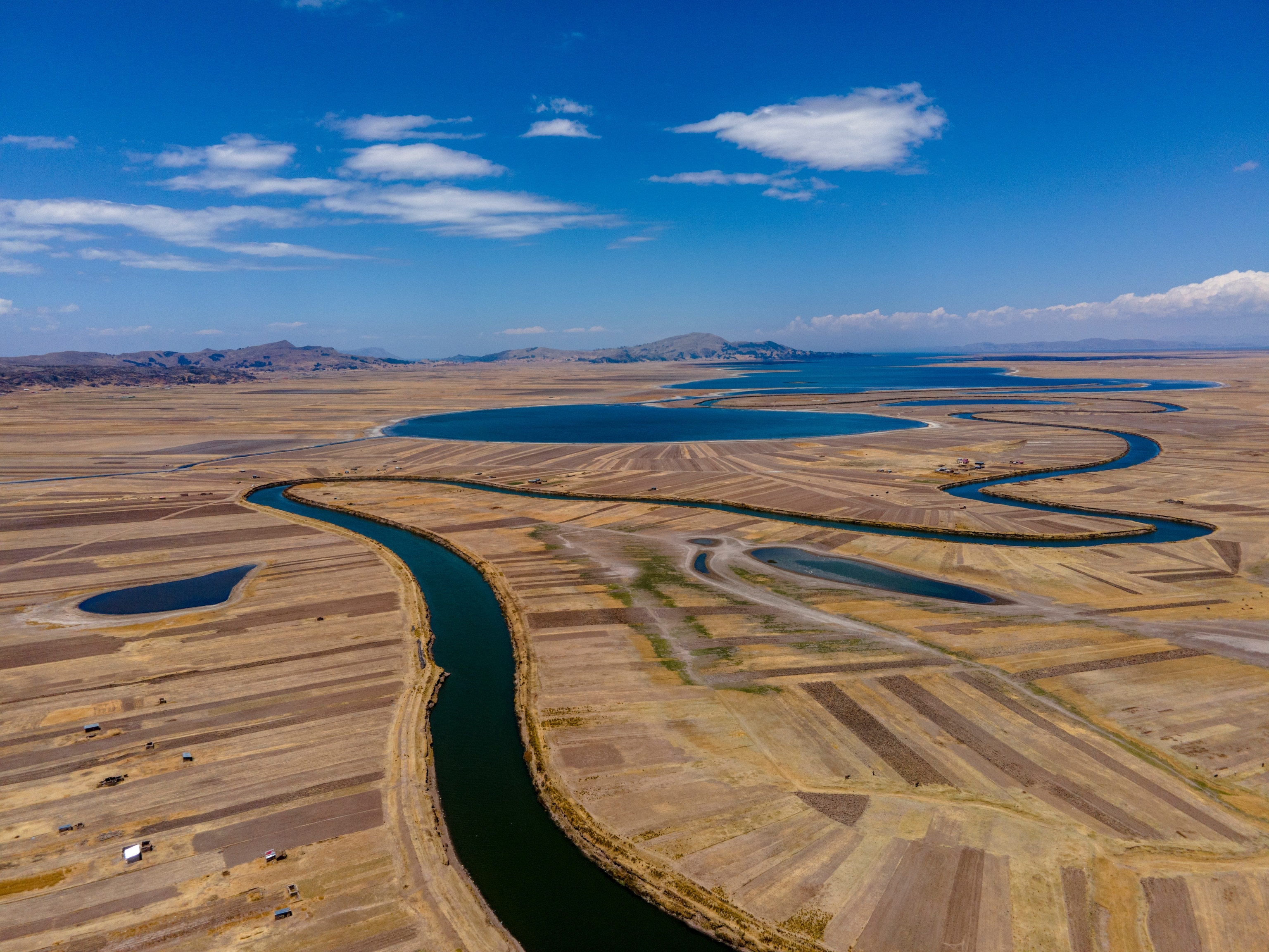 Aerial view of the mouth of the Coata River into Lake Titicaca, Peru. The Coata basin, one of the 13 that flows into Titicaca, is contaminated. The river itself contains lead, arsenic, zinc, thallium, phosphorus, among others. According to screenings conducted in 2021 by the Ministry of Health, 83.5% of the population in the district tested had arsenic levels in their urine above the permitted range. This is because the inhabitants consumed water and ate foods grown in the surrounding areas.
