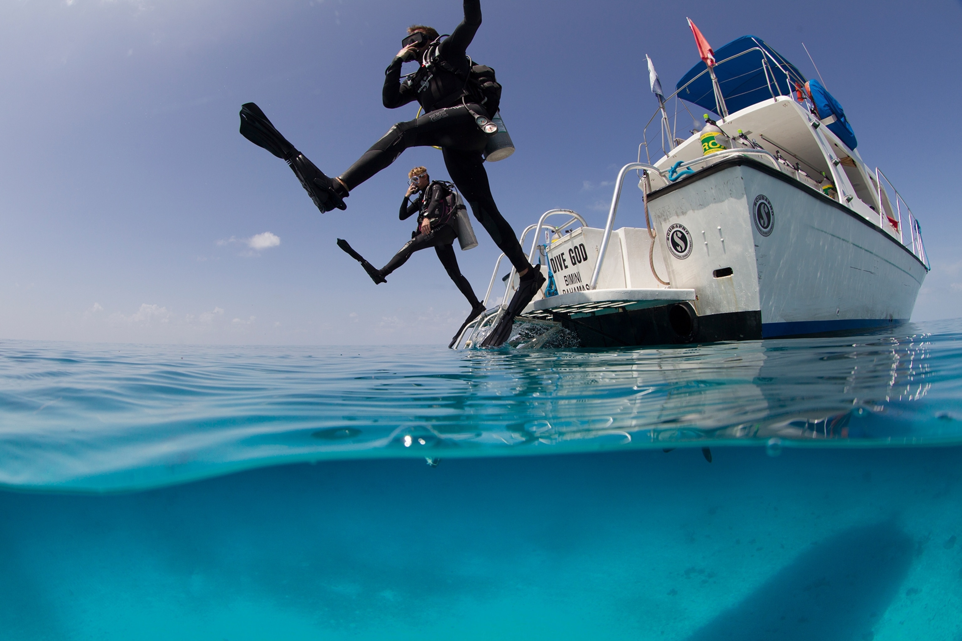 two scuba divers jumping into the sea
