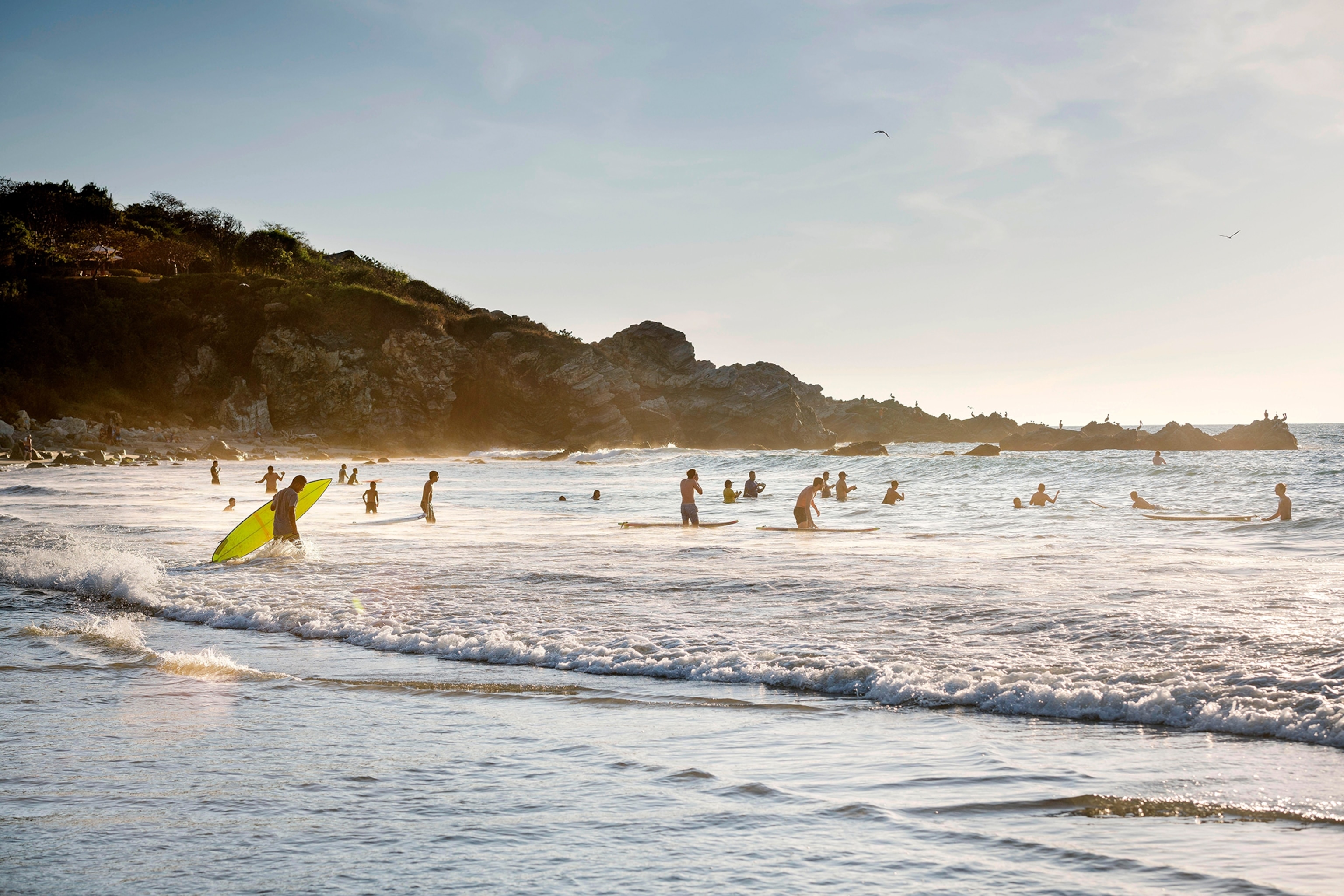 A shallow beach with plenty of surfers and bathers.