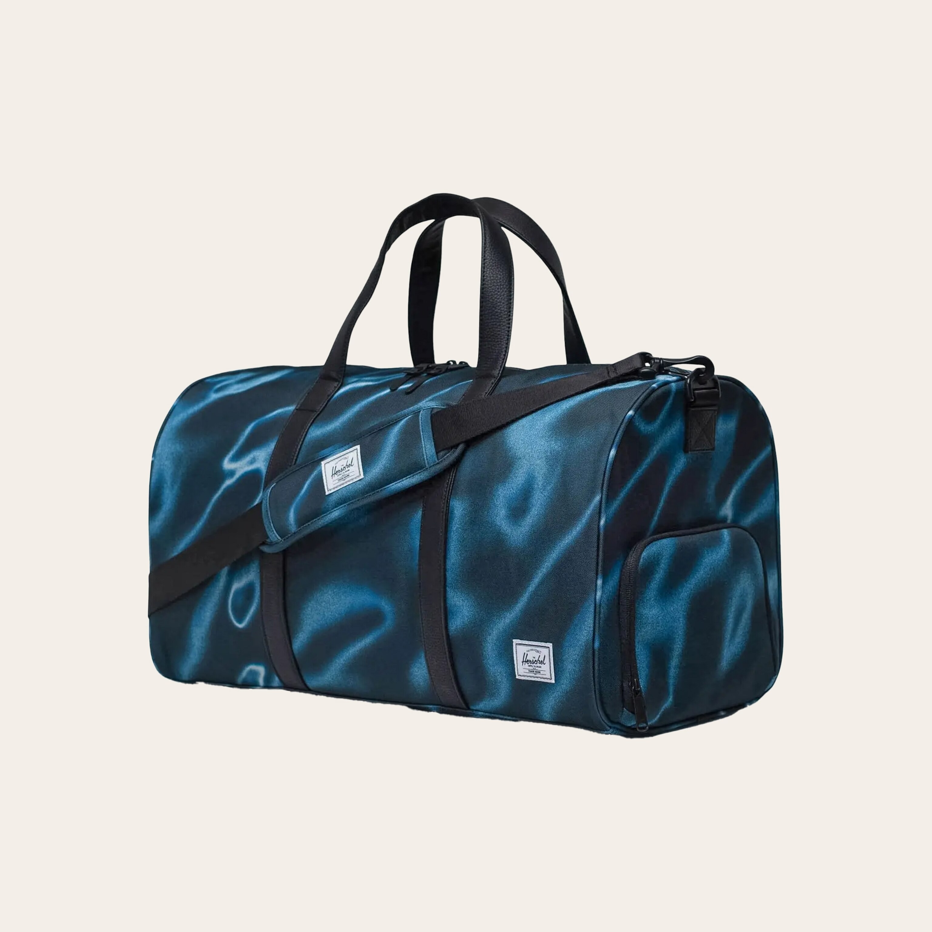 A duffel bag with a black and blue marble pattern, against a tan background.