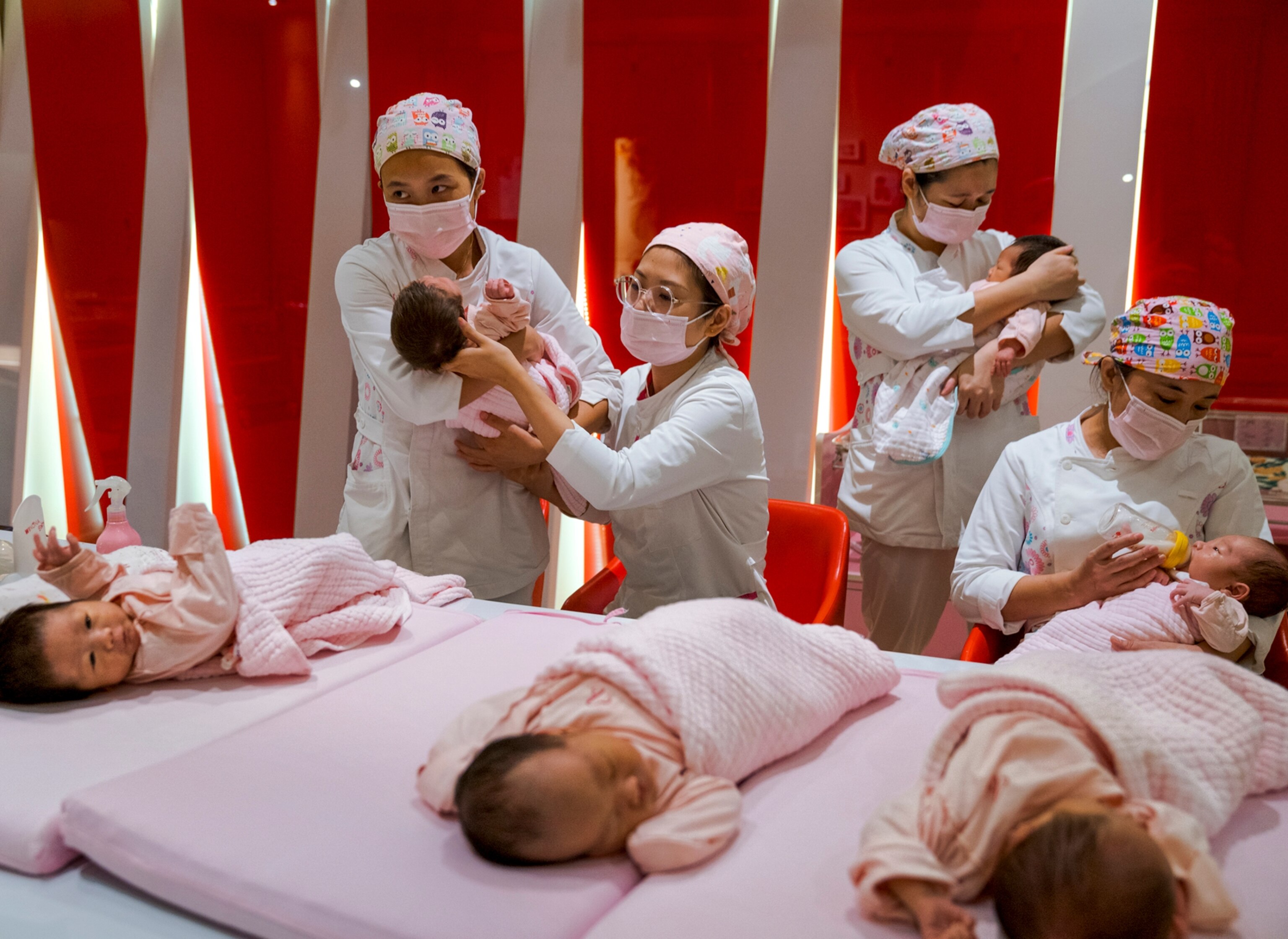 Picture of multiple nurses taking care of multiple newborns.