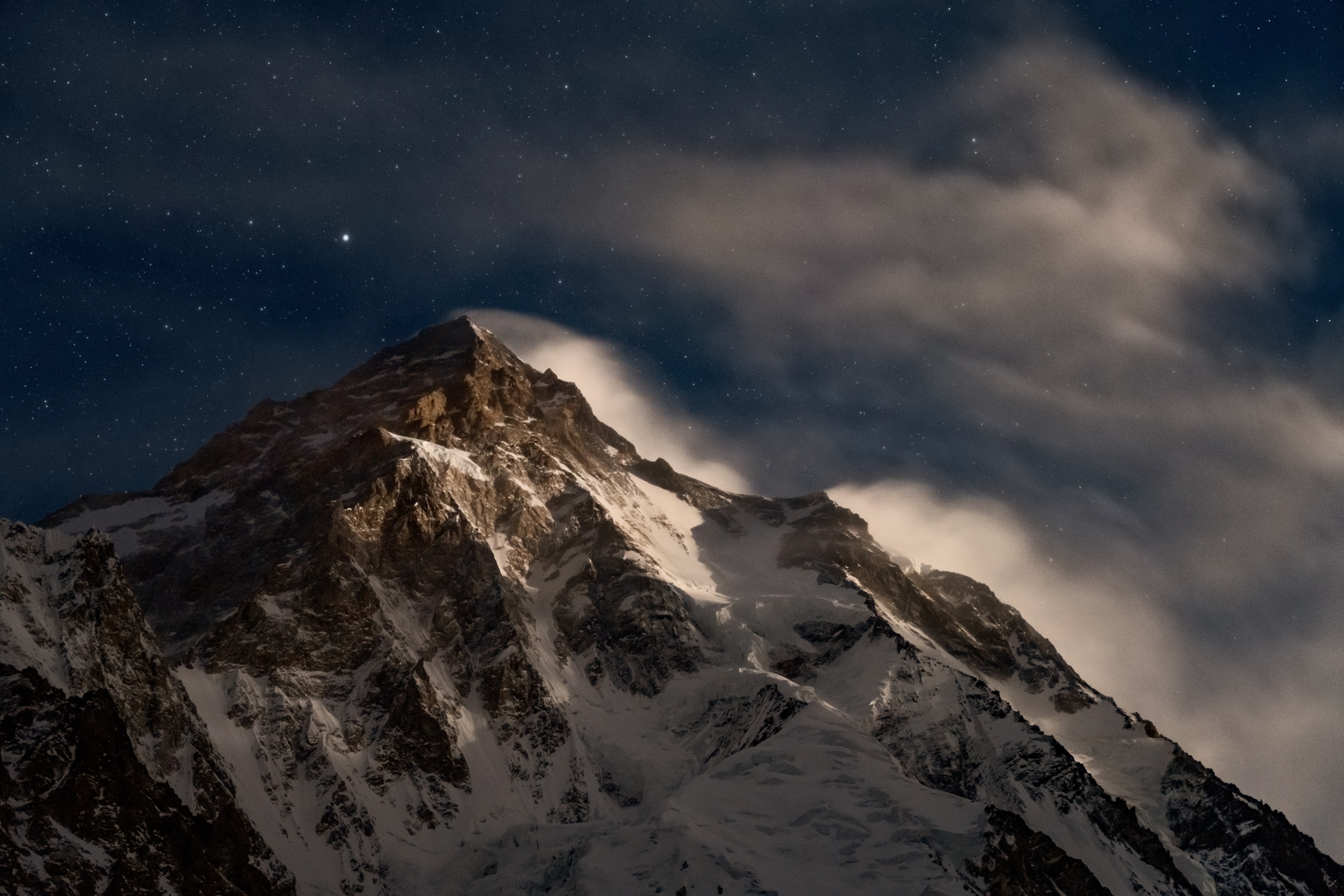 Picture of the mountain covered with snow and ice and clouds above it.