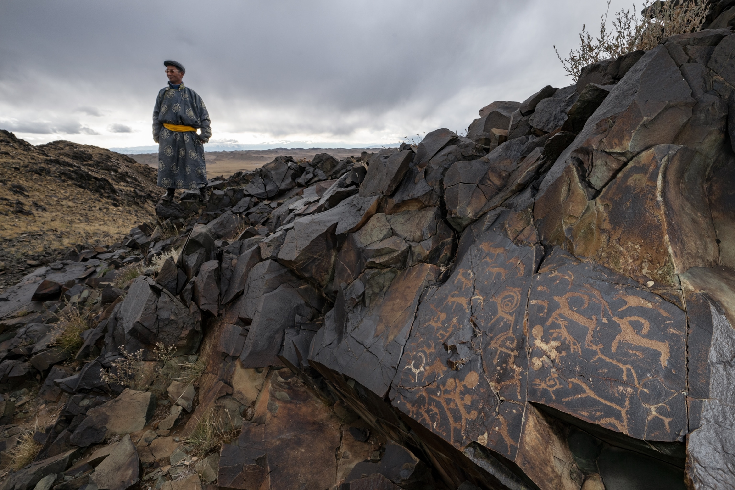 Bazar Losol looks at petroglyphs of ibex and gazelles on a hill