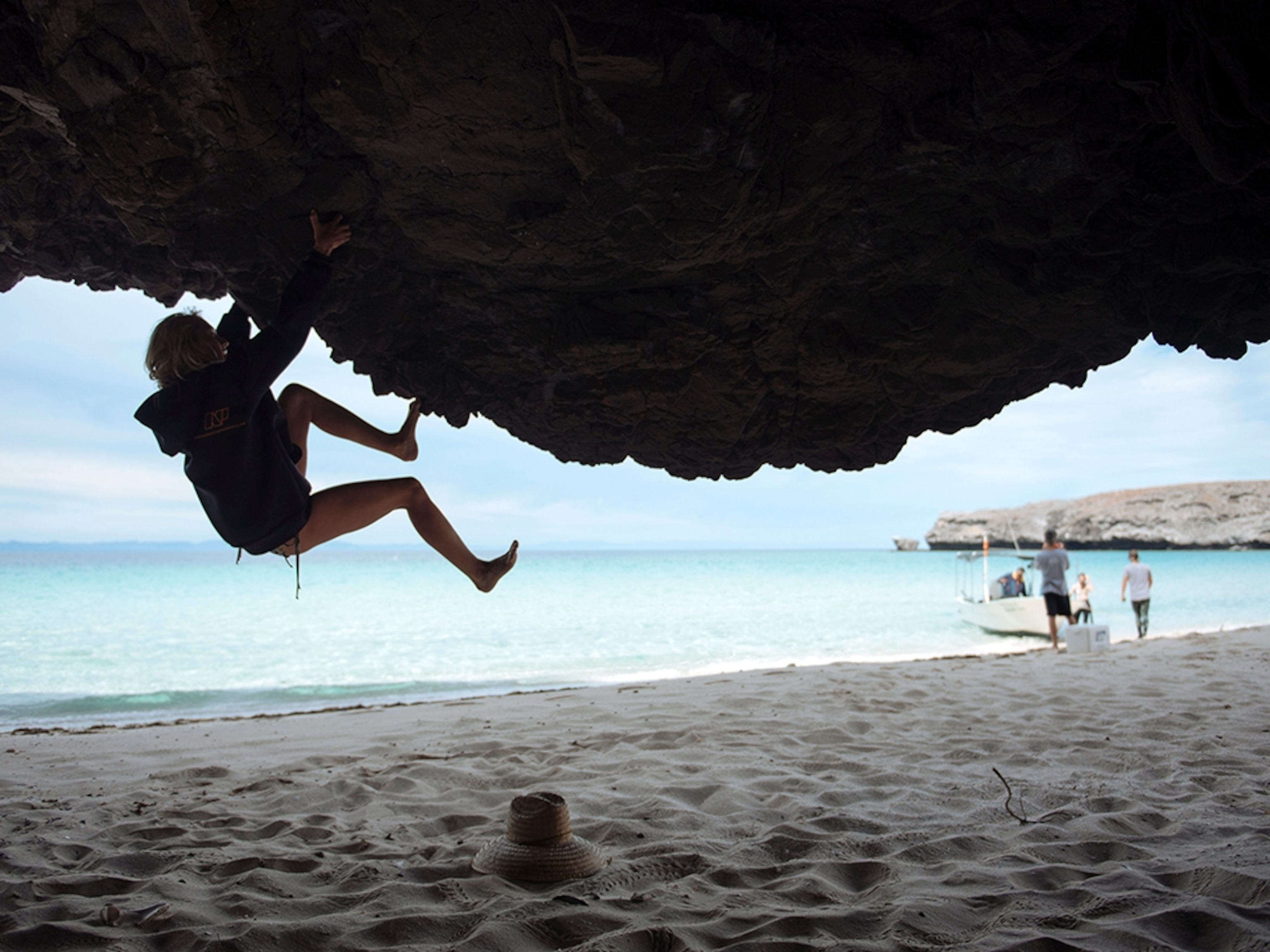 a woman climbing an overhanging cliff on the beach near La Paz, in Baja, Mexico