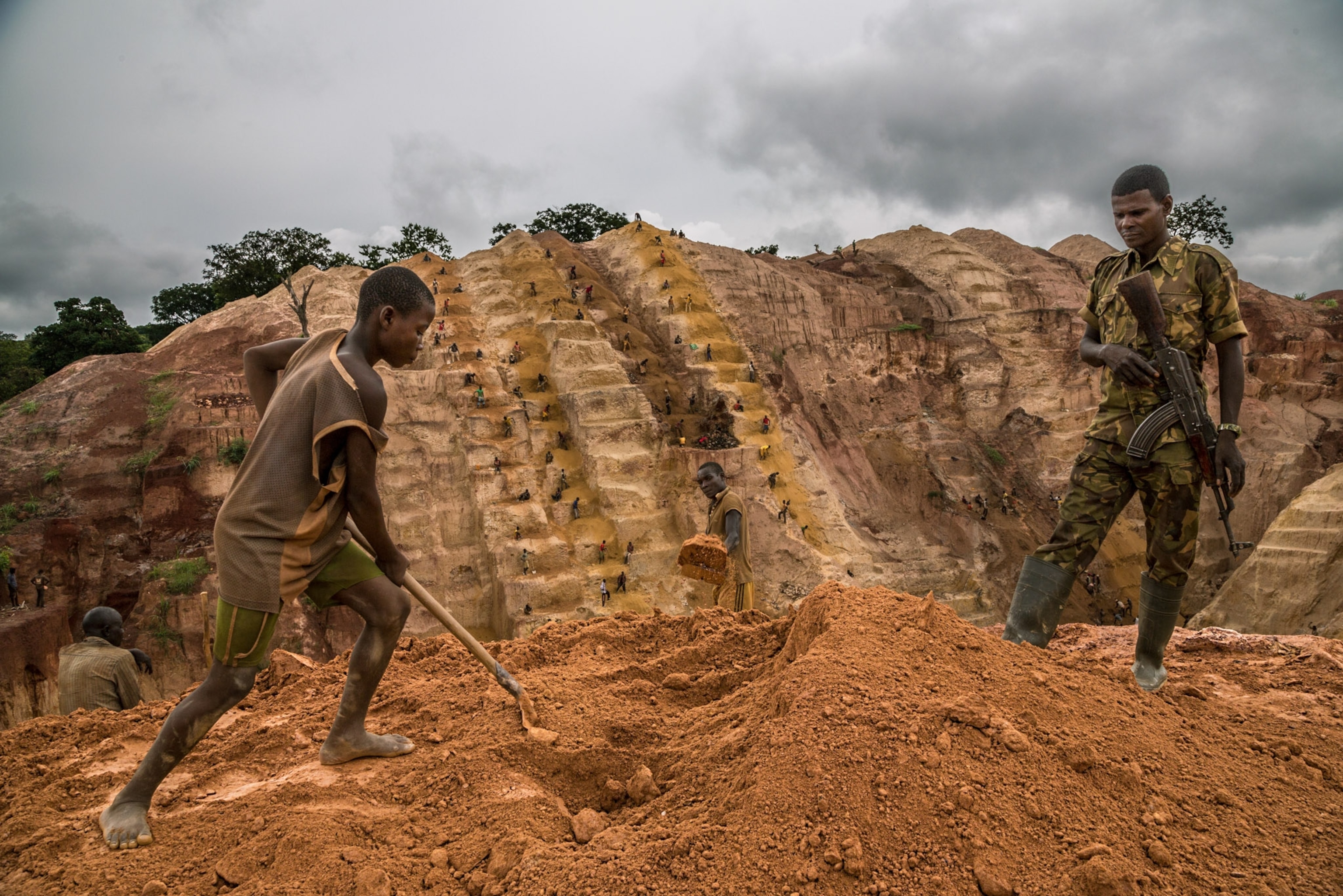 a muslim rebel standing guard over a young boy working in a gold mine near Bambari