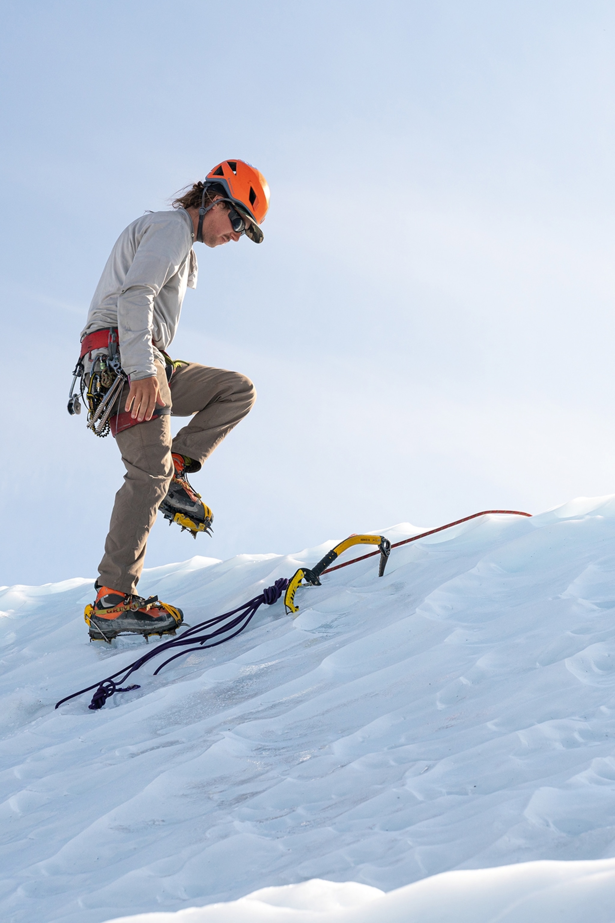 A male hiker with snow hiking equipment on an icy cliff's edge.
