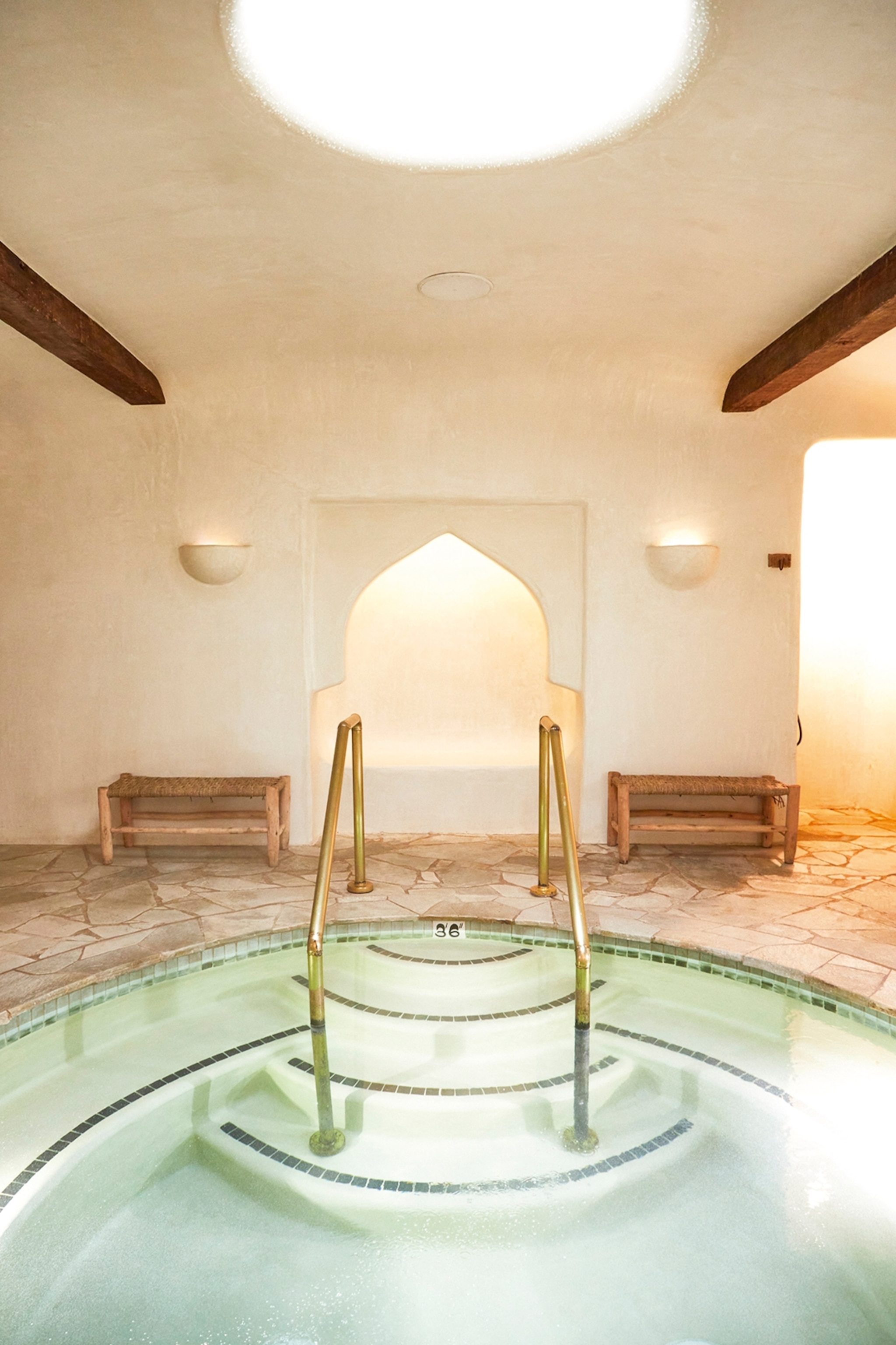 Steps leading into a jacuzzi surrounded by white walls and soft warm lighting