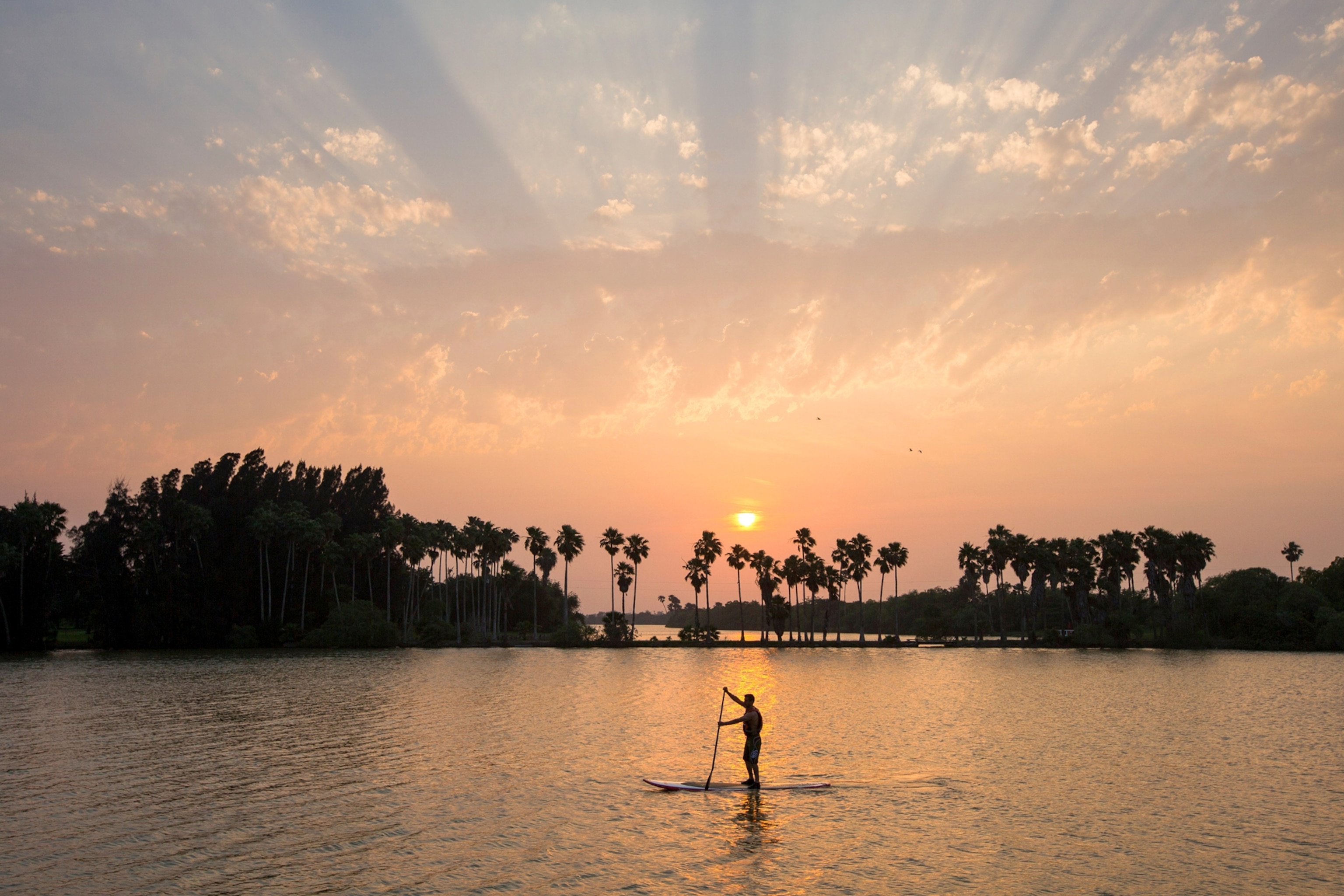 Carlos Nuñez paddling his standup paddle board across a lake near Brownsville, Texas