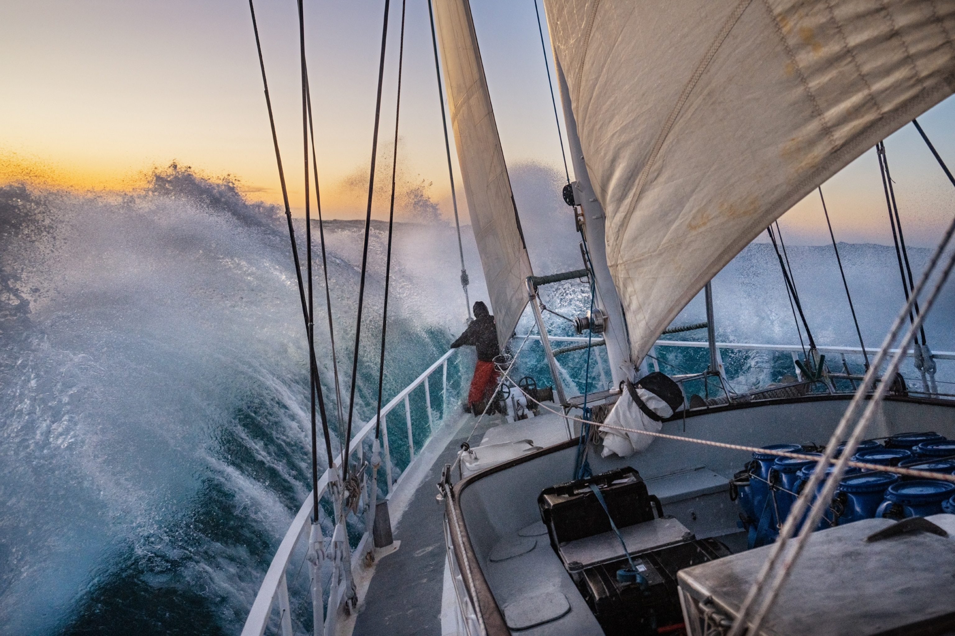 Person on the bow looking at the horizon as sailboat going through the stormy seas.