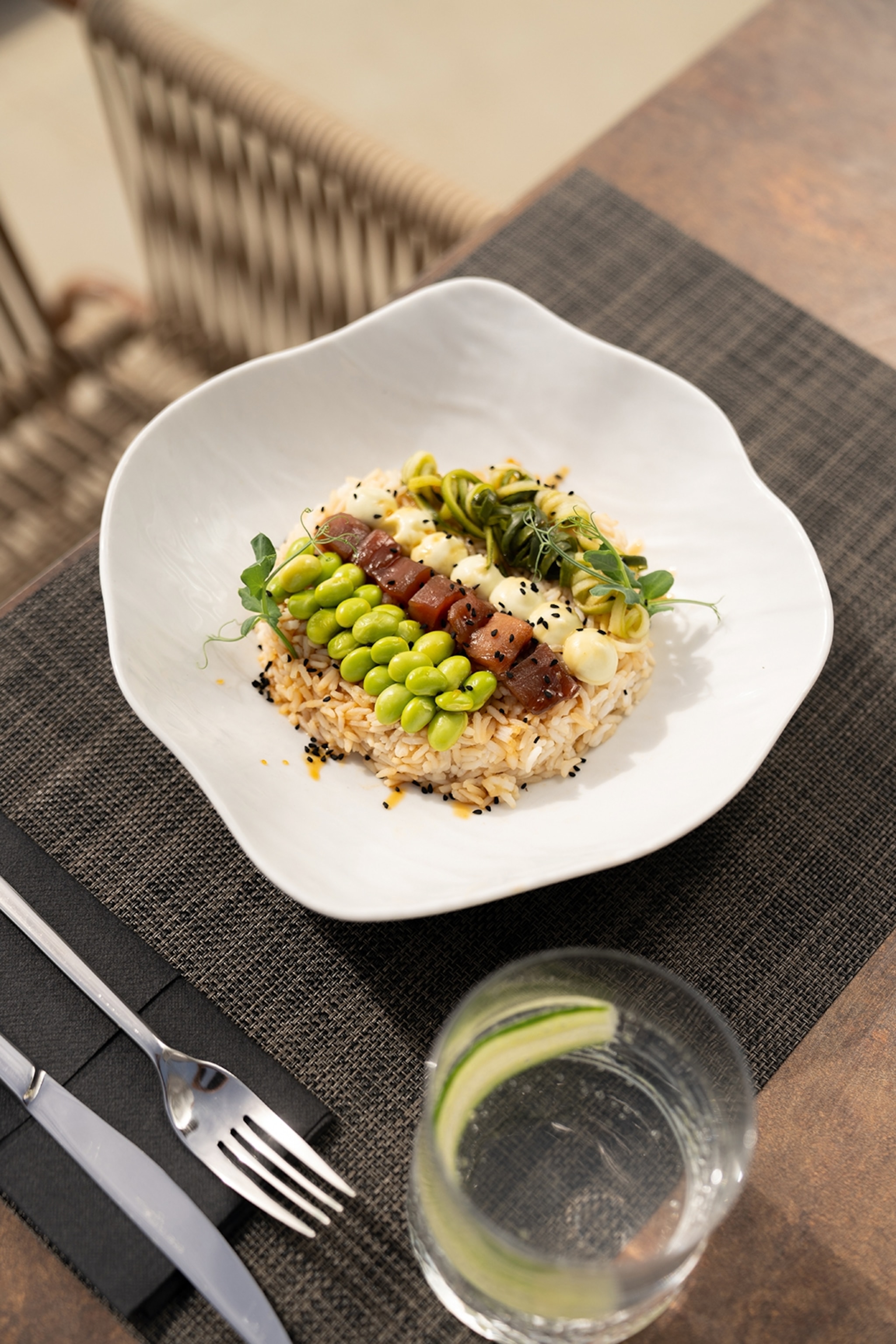 Bowl filled with rice topped with raw tuna, green beans and vegetables