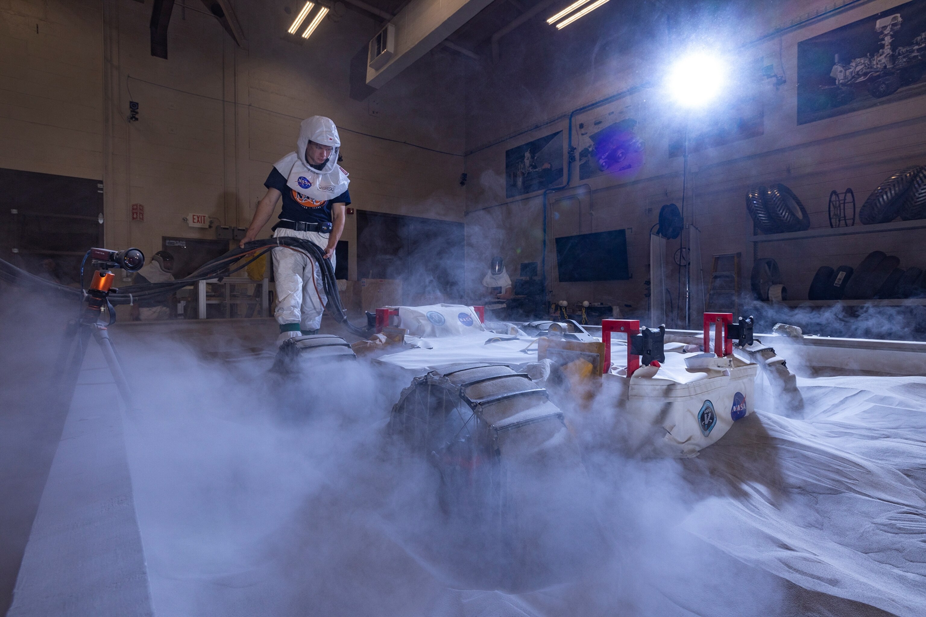 Dust and sand are displaced into the air as a NASA rover prototype is tested in simulated lunar soil.